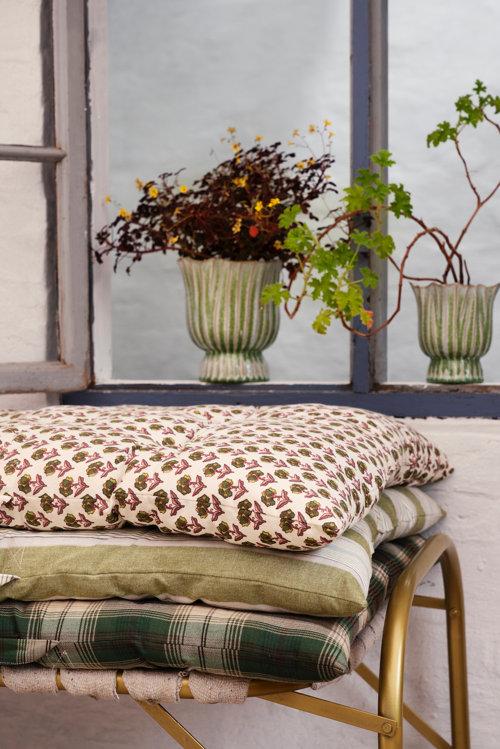 Decorative pillows on a bench with plants in the background