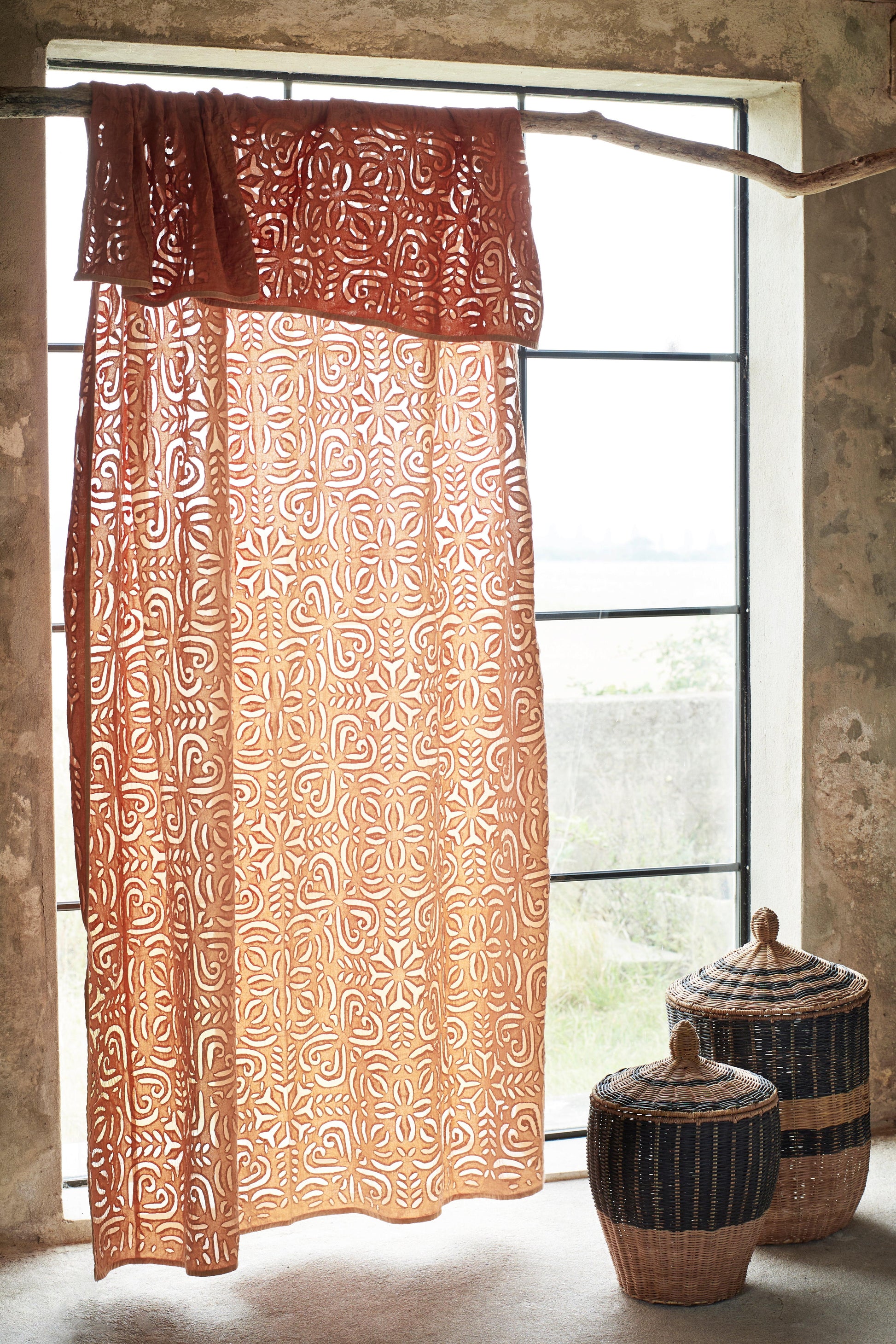 Patterned throw with decorative baskets in front of a window.