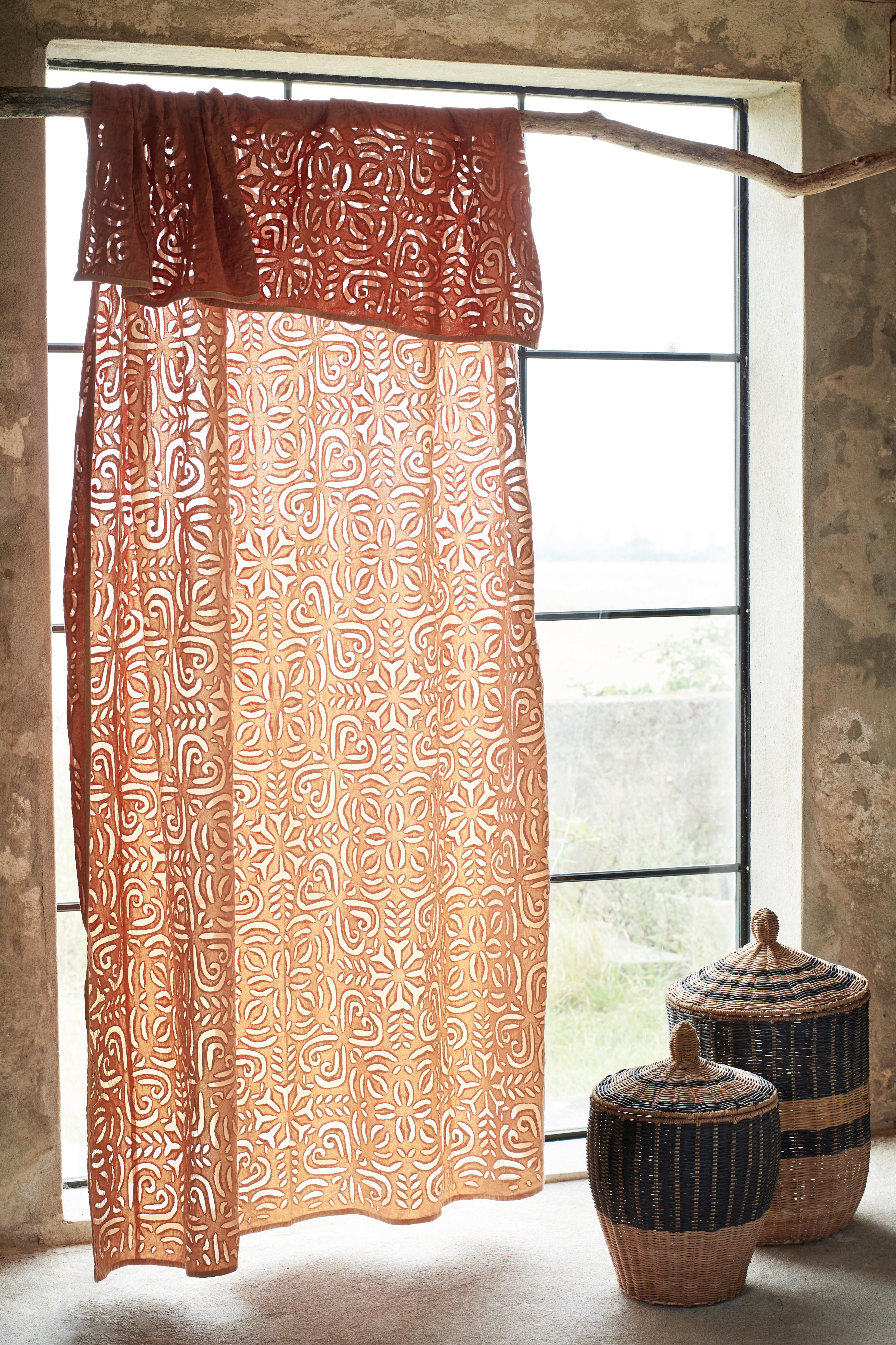 Patterned throw with decorative baskets in front of a window.