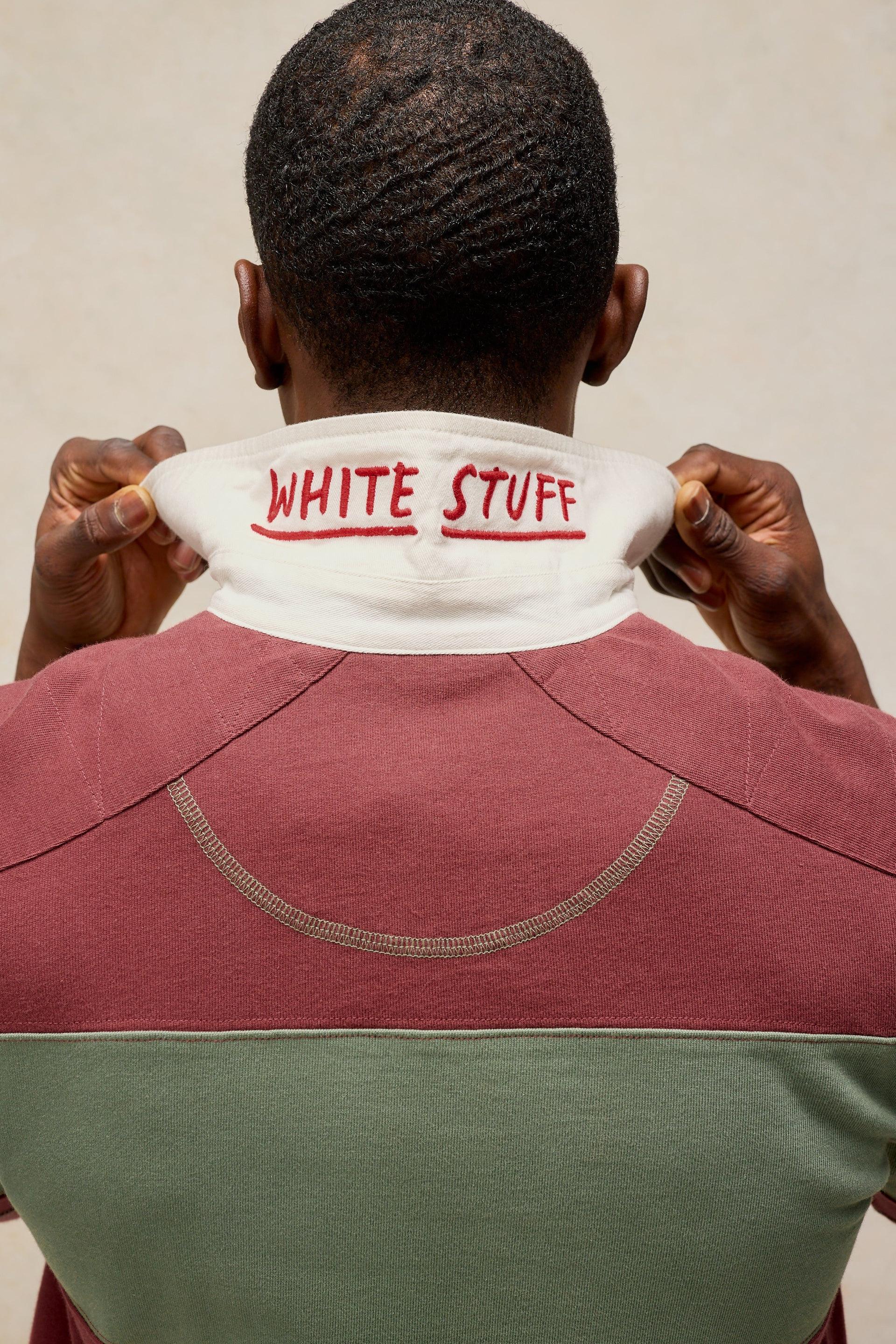 A person shown from behind wearing a color-blocked pullover shirt with a white collar. The collar features the words 'WHITE STUFF' printed in red across the neck.
