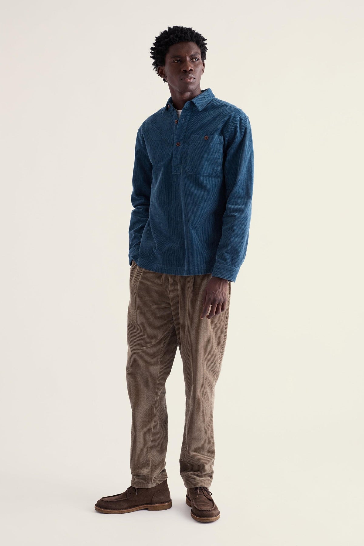 A man wearing a blue organic cotton cord pull over shirt from Seasalt Cornwall, styled with brown corduroy trousers.