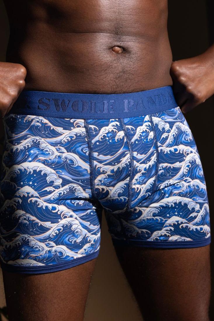 Close-up of a man wearing blue sea-themed Swole Panda bamboo boxers with a wave pattern.