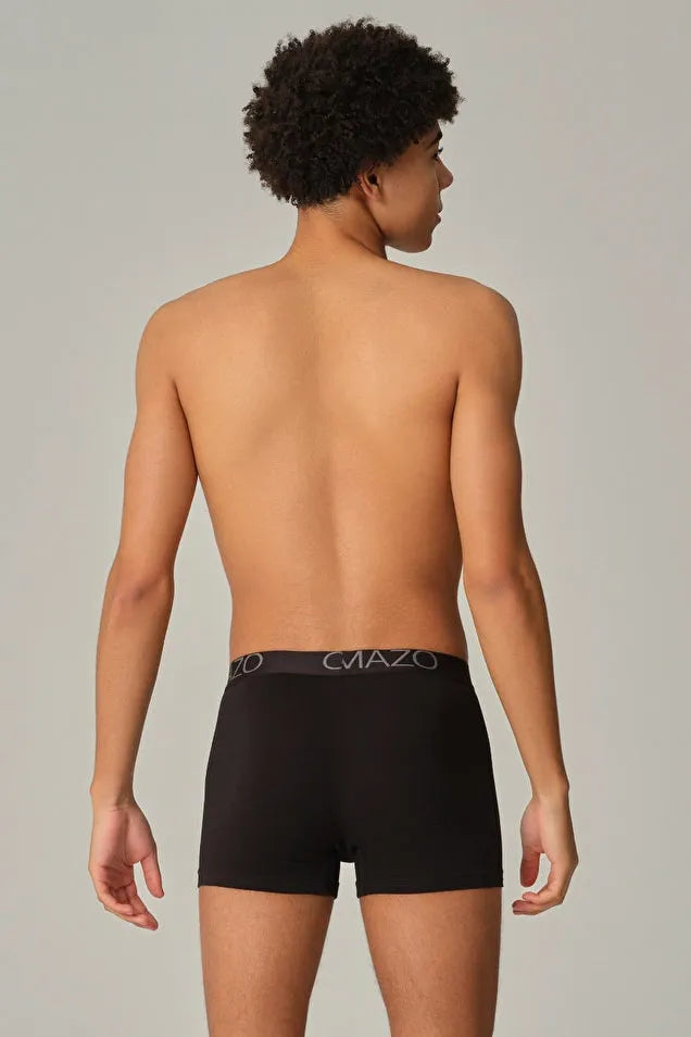 A man wearing Comazo organic cotton black boxer briefs, viewed from the back against a neutral background.