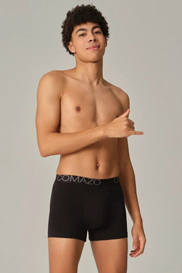 Young man posing in Comazo organic cotton black boxer briefs against a neutral background.