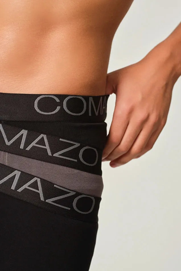Close-up of a man wearing Comazo organic cotton black boxer briefs with logo waistband.
