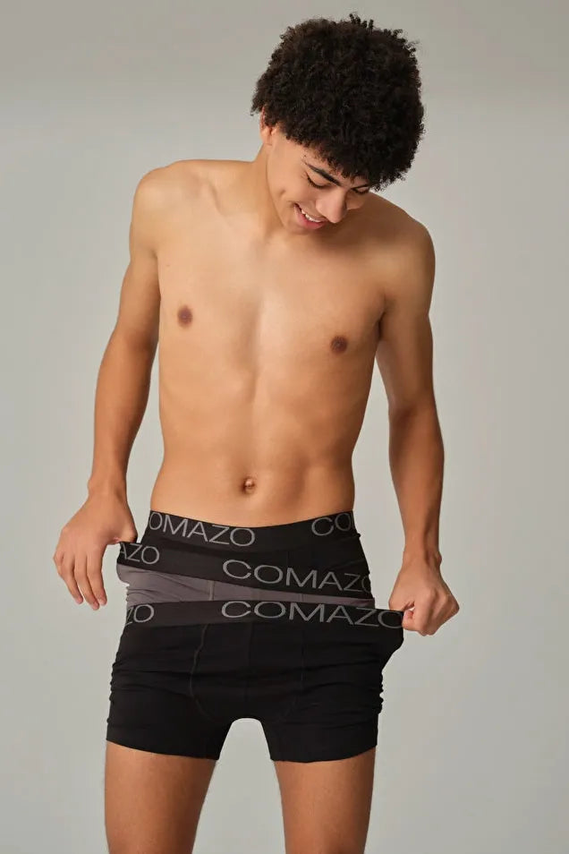 Young man smiling while wearing layered Comazo organic cotton boxer briefs.