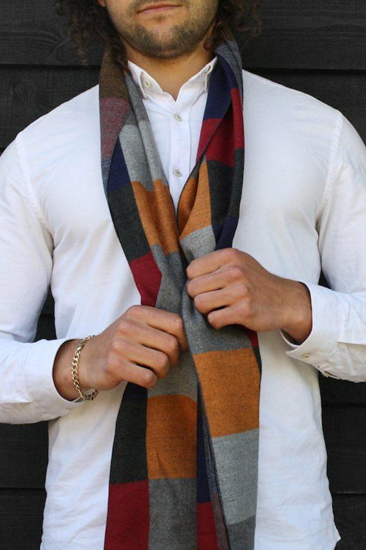 A man wearing a stylish multicolored Swole Panda winter scarf over a white button-down shirt.