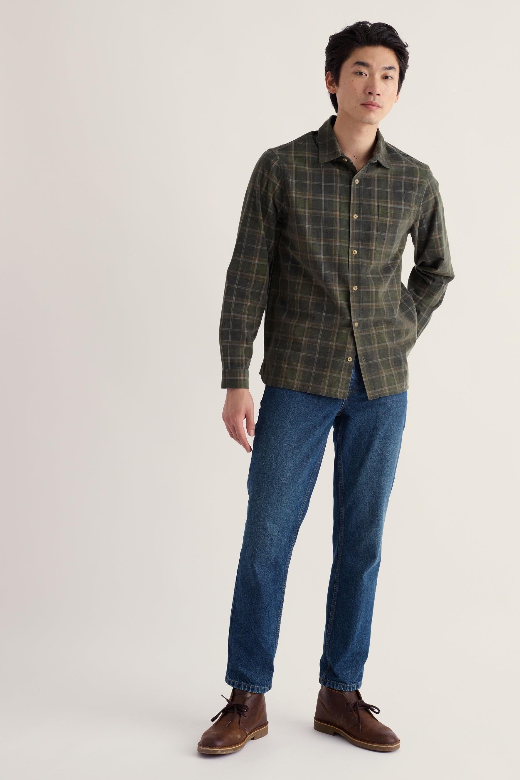 A man wearing a casual outfit of a check shirt and blue jeans