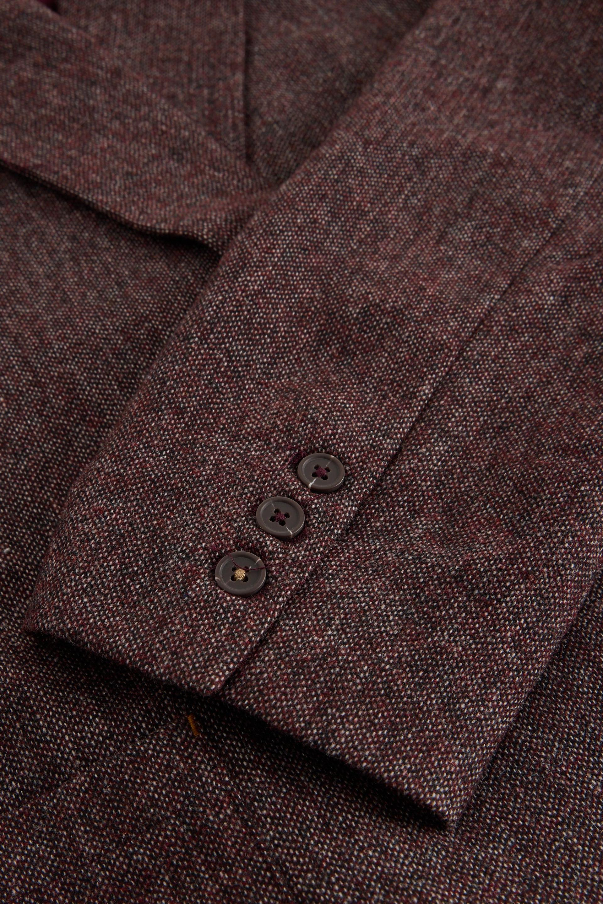 Close-up of a textured tweed blazer sleeve in a dark reddish-brown color, featuring three dark buttons on the cuff.
