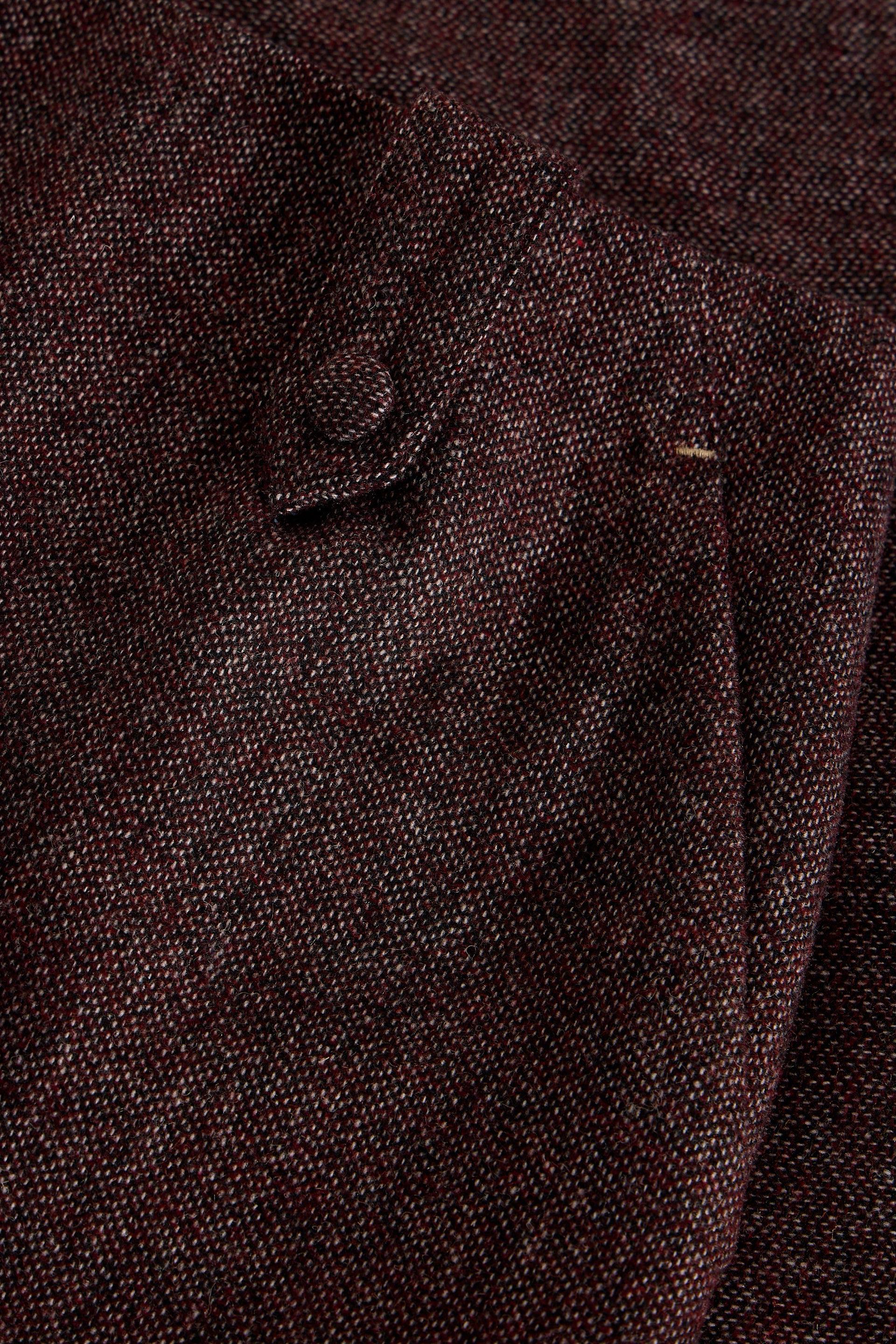 Close-up of a plum textured fabric with a small button detail and a subtle woven pattern.