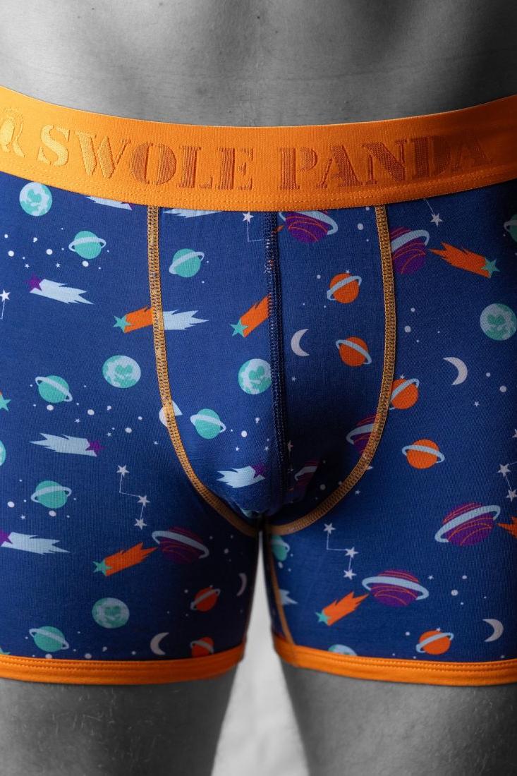 Close-up of a man wearing blue breathable bamboo boxers with an orange waistband and outer space print pattern.
