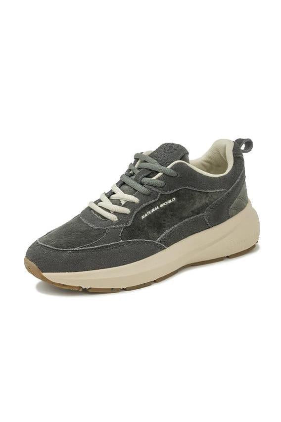 A dark gray suede and mesh sneaker with off-white laces and a thick cream-colored midsole, shown from a side profile on a white background.