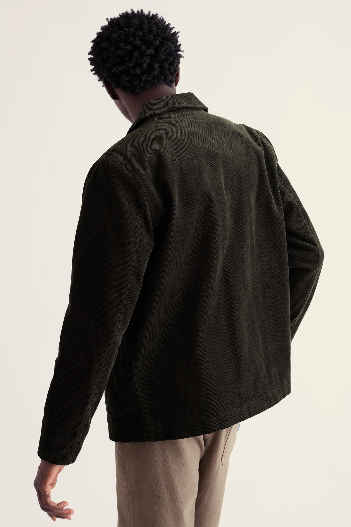 A man wearing an olive green organic cotton blazer seen from the back.