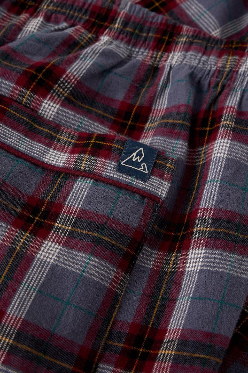 Close up of White Stuff men's pyjama trousers in a plum check organic cotton pattern with a branded logo tab.