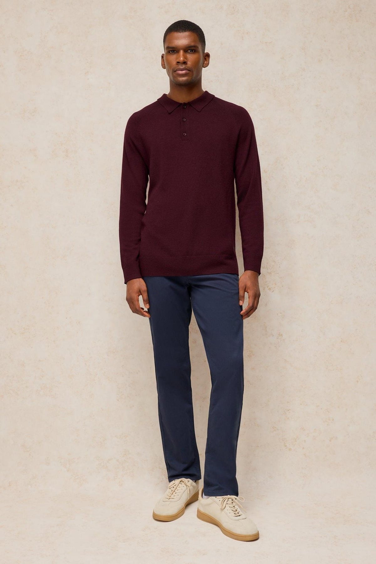 A man wearing a long-sleeved plum merino wool polo shirt from White Stuff.