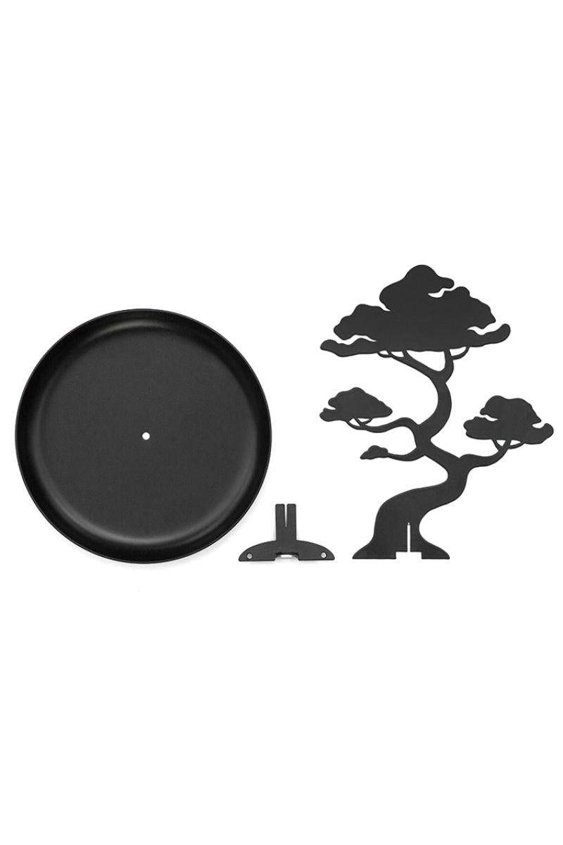 Black metal bonsai tree jewellery stand and round decorative plate on a white background