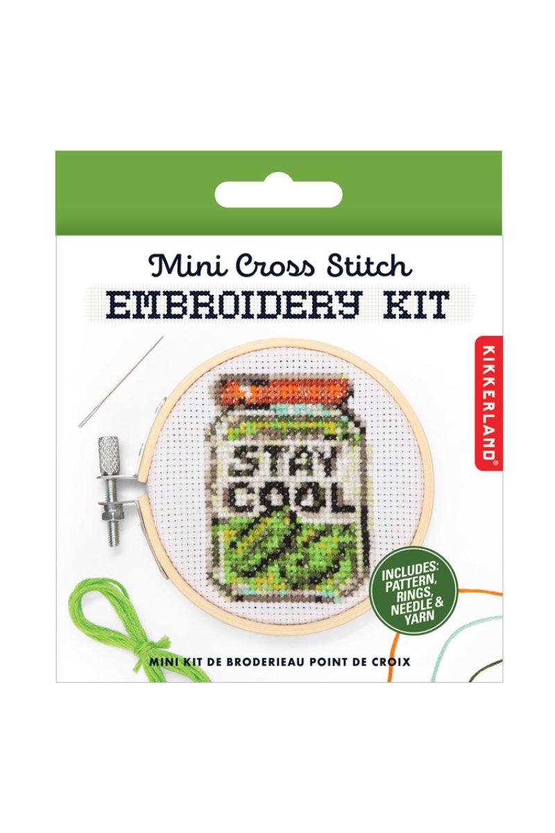 Kikkerland Mini Cross Stitch Embroidery Kit in its retail packaging, featuring a wooden hoop with a 'STAY COOL' jar design, a green thread spool, and a needle on a white background with a green header.