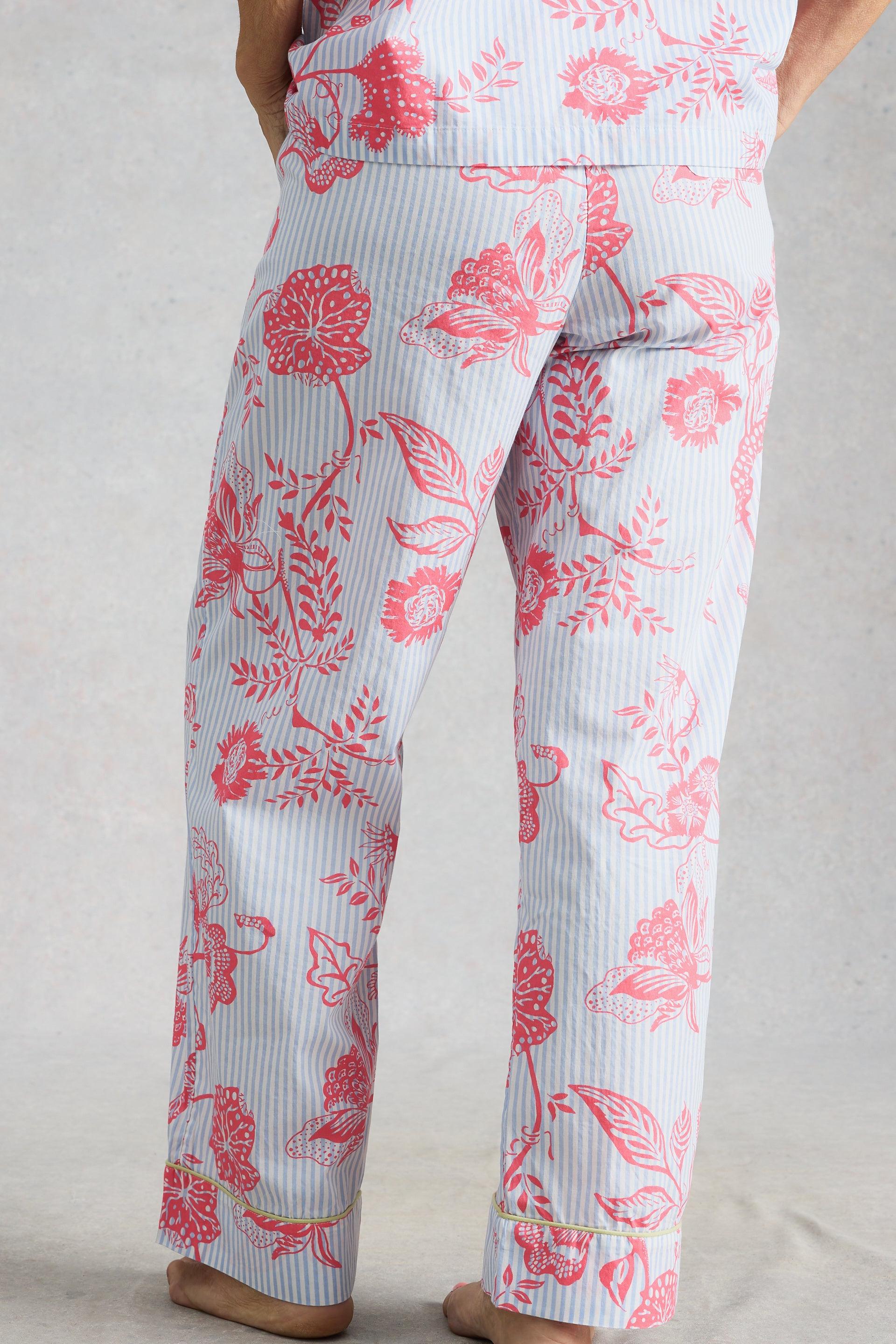 A model standing in floral patterned organic cotton pyjamas against a neutral background.