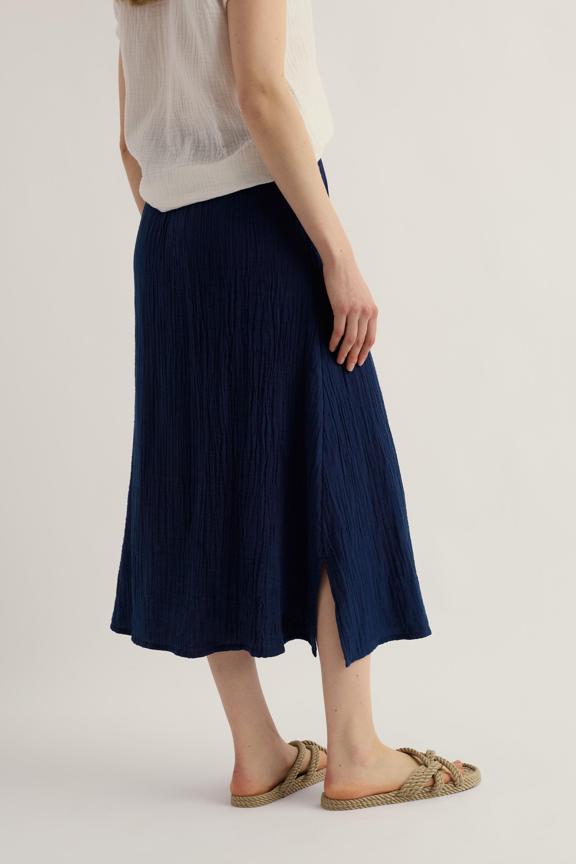 Person wearing a navy pleated skirt on a plain background