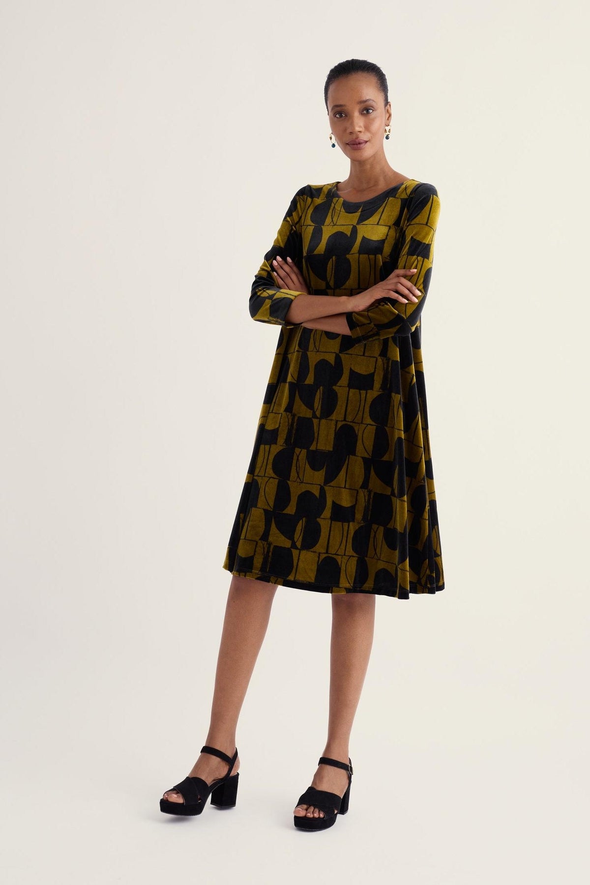 A model stands wearing a patterned Seasalt Cornwall velvet dress, suitable as a winter party dress.