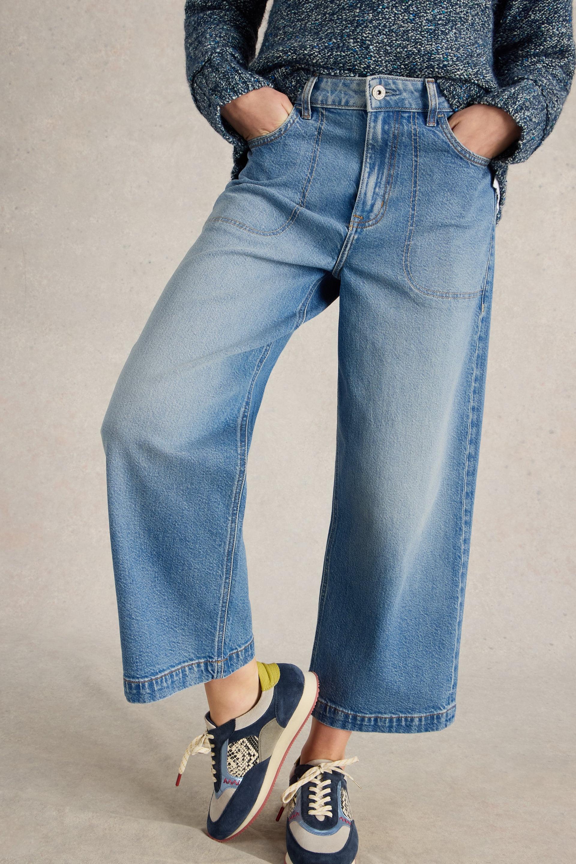 Model wearing wide-leg blue denim jeans and textured sweater with casual sneakers