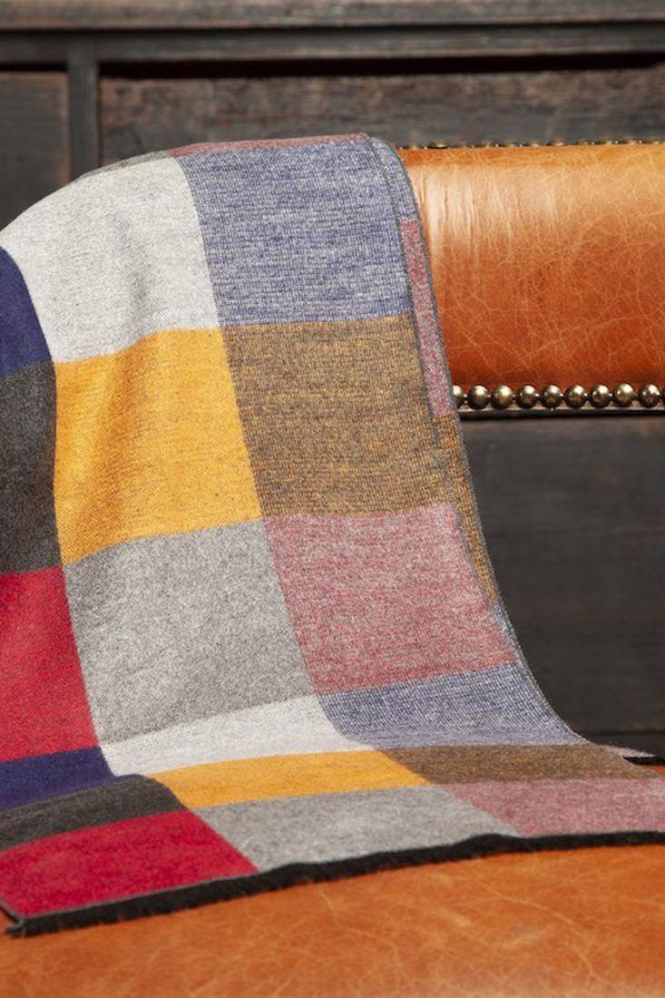 A colorful checkered Swole Panda winter scarf draped over a vintage leather chair.