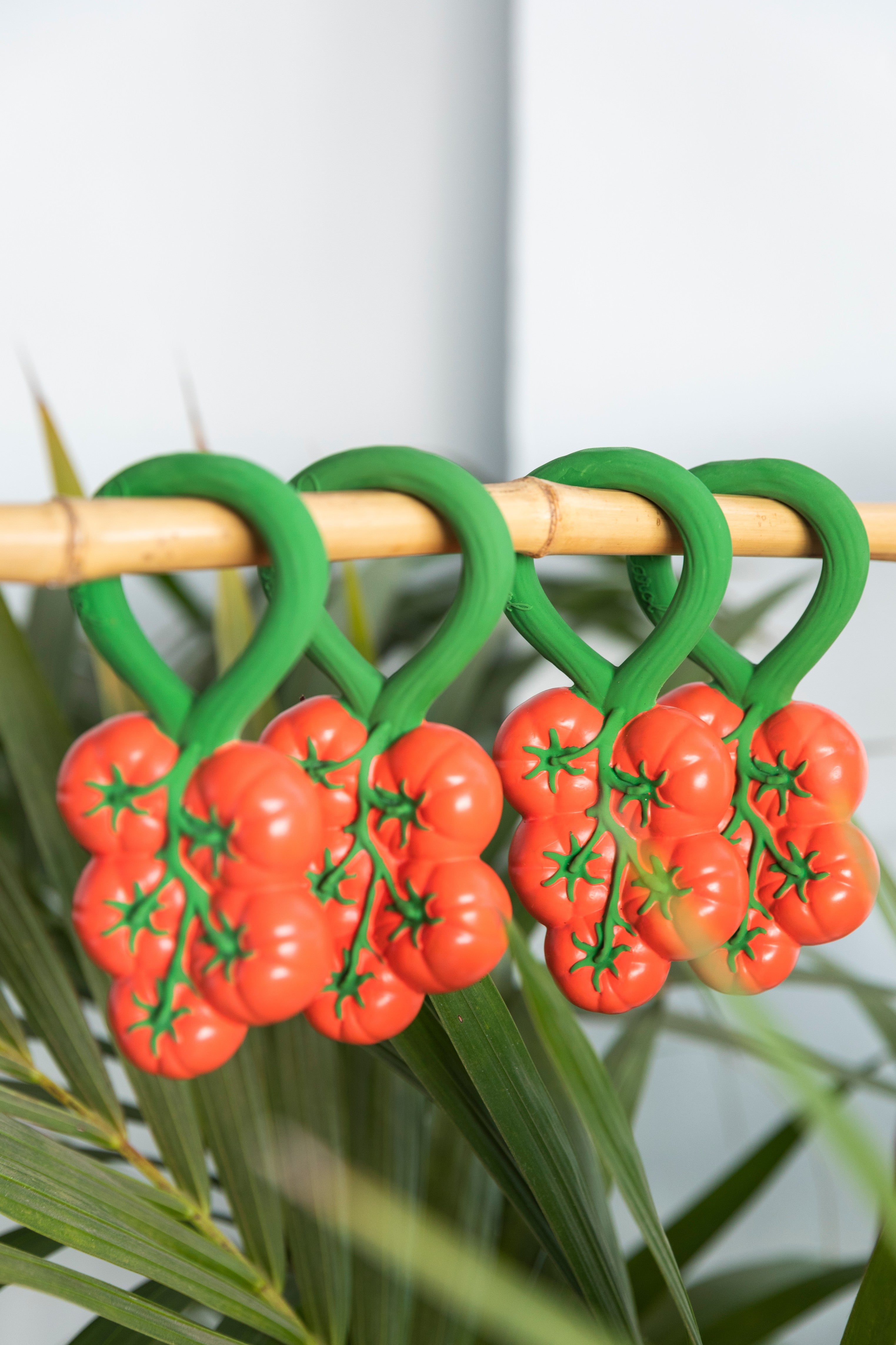 Handcrafted natural rubber tomato baby rattles and teethers on a pole.