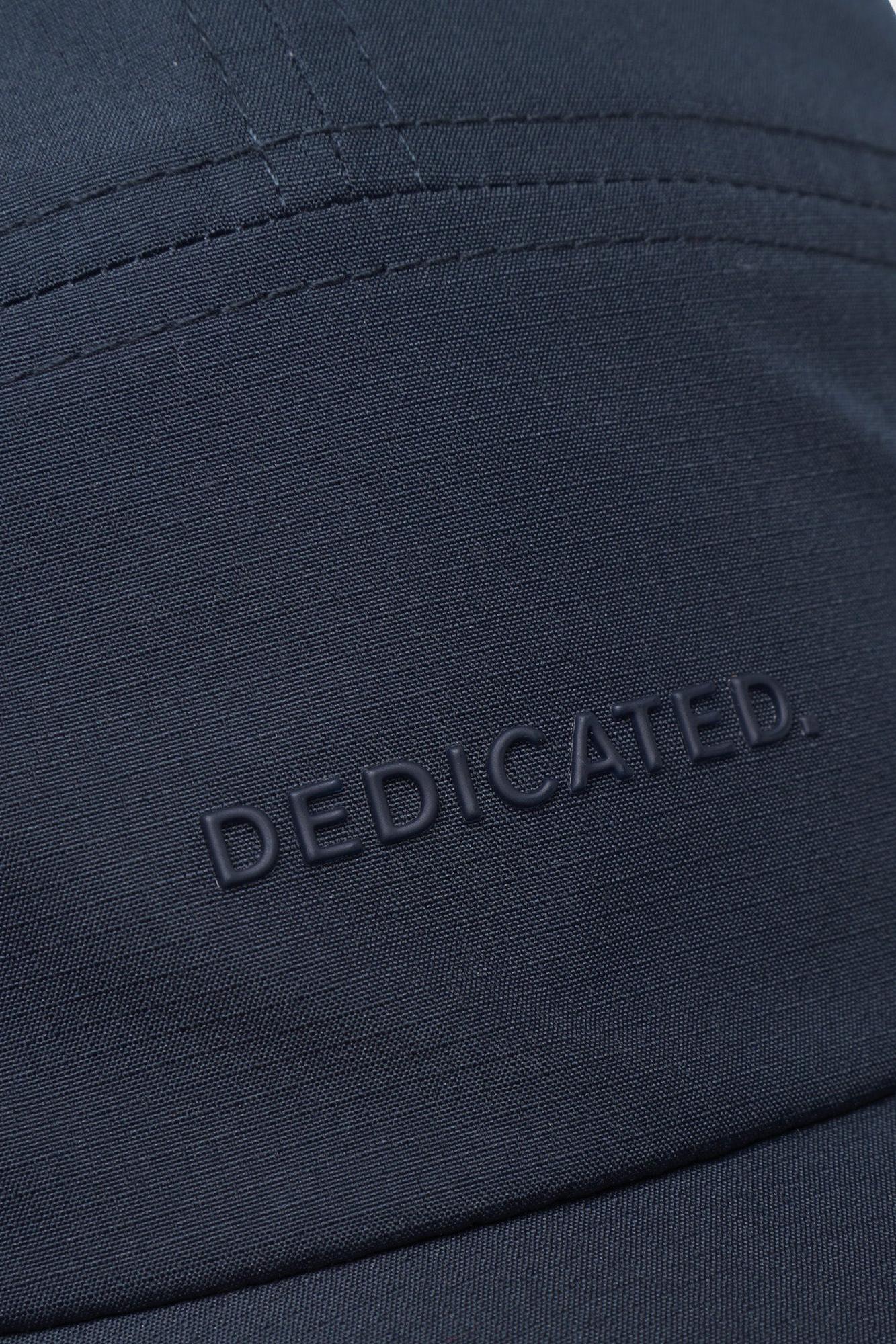 Close-up of a dark navy blue fabric cap with the word 'DEDICATED.' embossed on the front, showing fine stitching and texture.