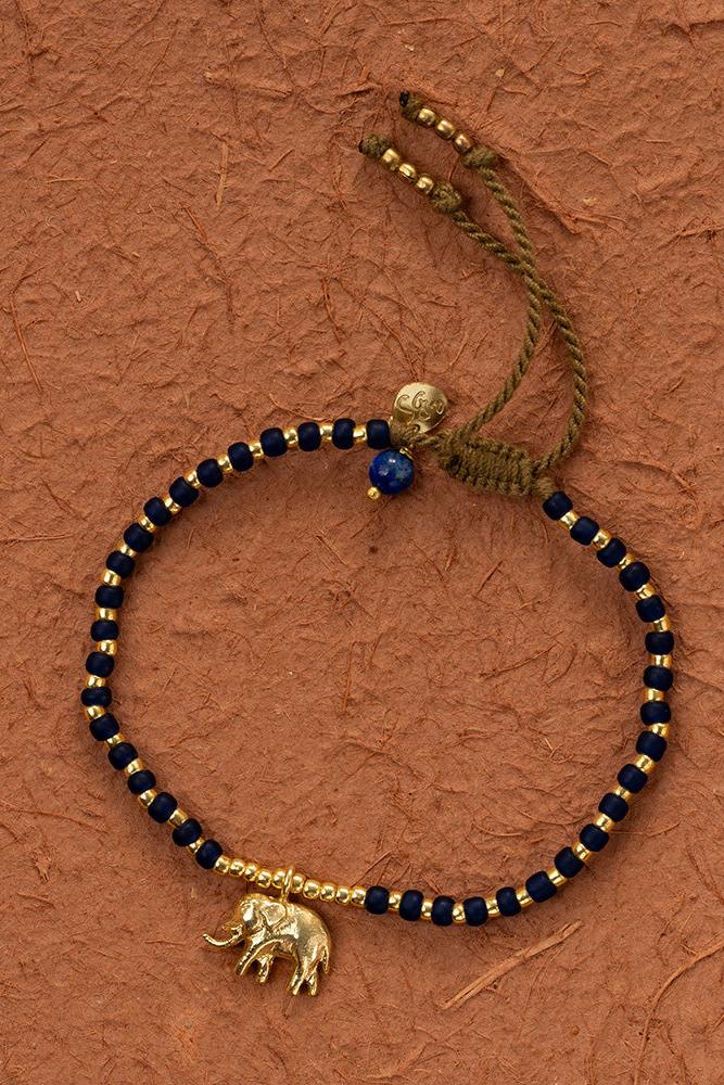 Bracelet with blue and gold beads and an elephant charm on a brown textured background