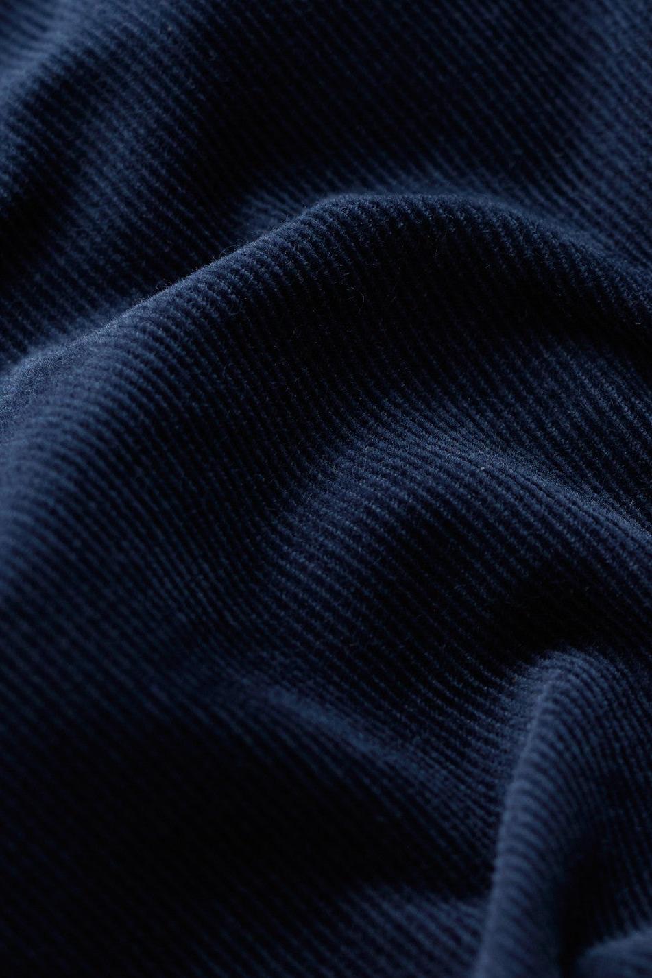 A close-up of dark navy blue ribbed fabric with soft folds and a smooth texture.