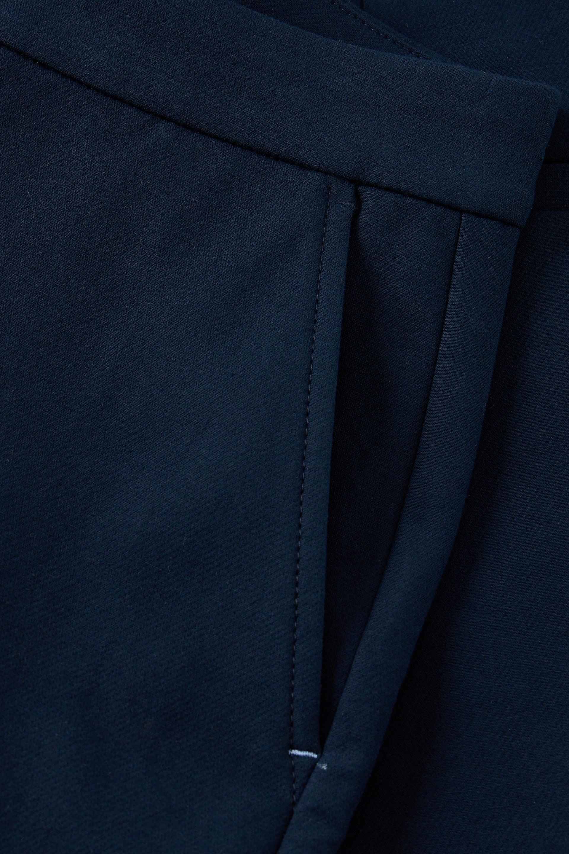 Close-up of dark navy blue fabric showing a side pocket seam and stitched edge detail.