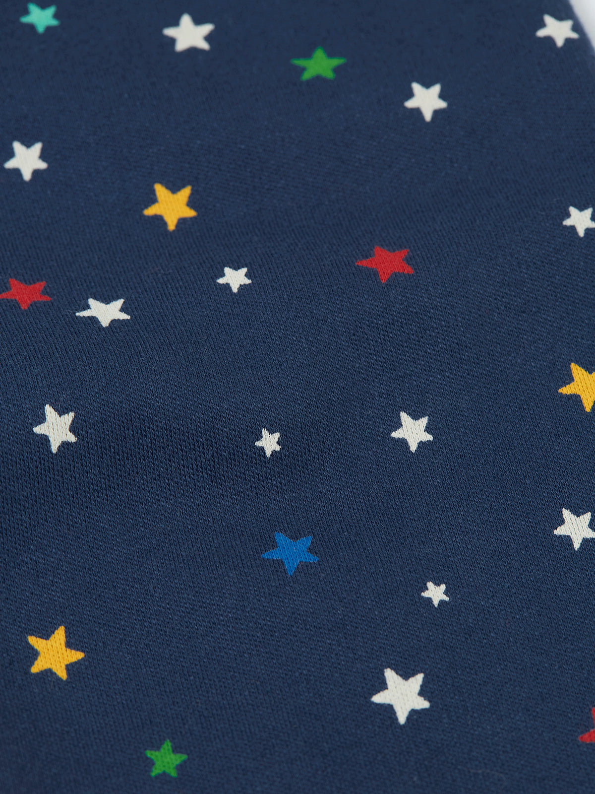 Close-up of navy blue organic cotton pyjamas featuring a vibrant, multi-colored star print pattern.