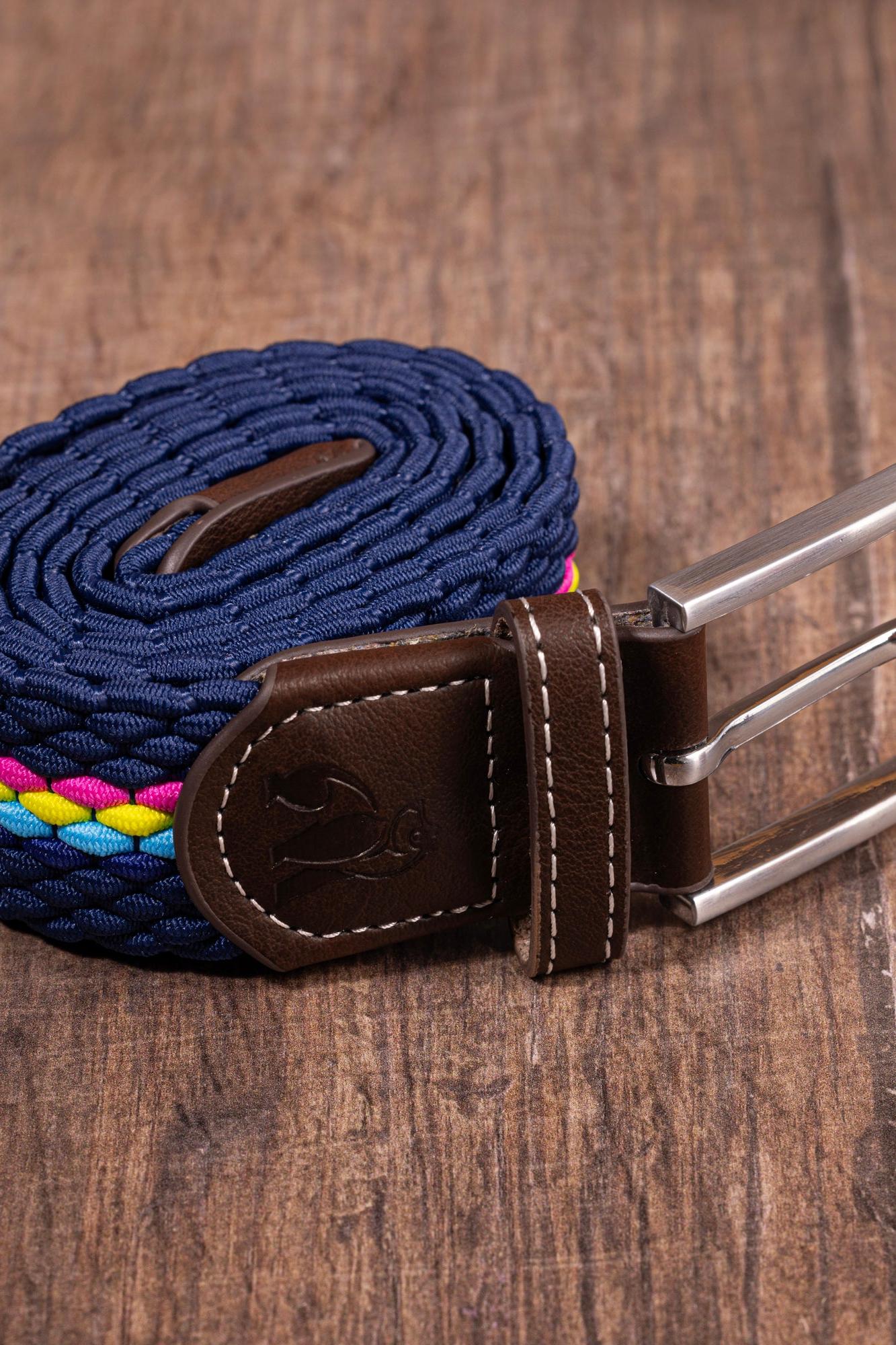 A coiled navy blue woven belt with brown leather trim and a silver metal buckle on a wood background.
