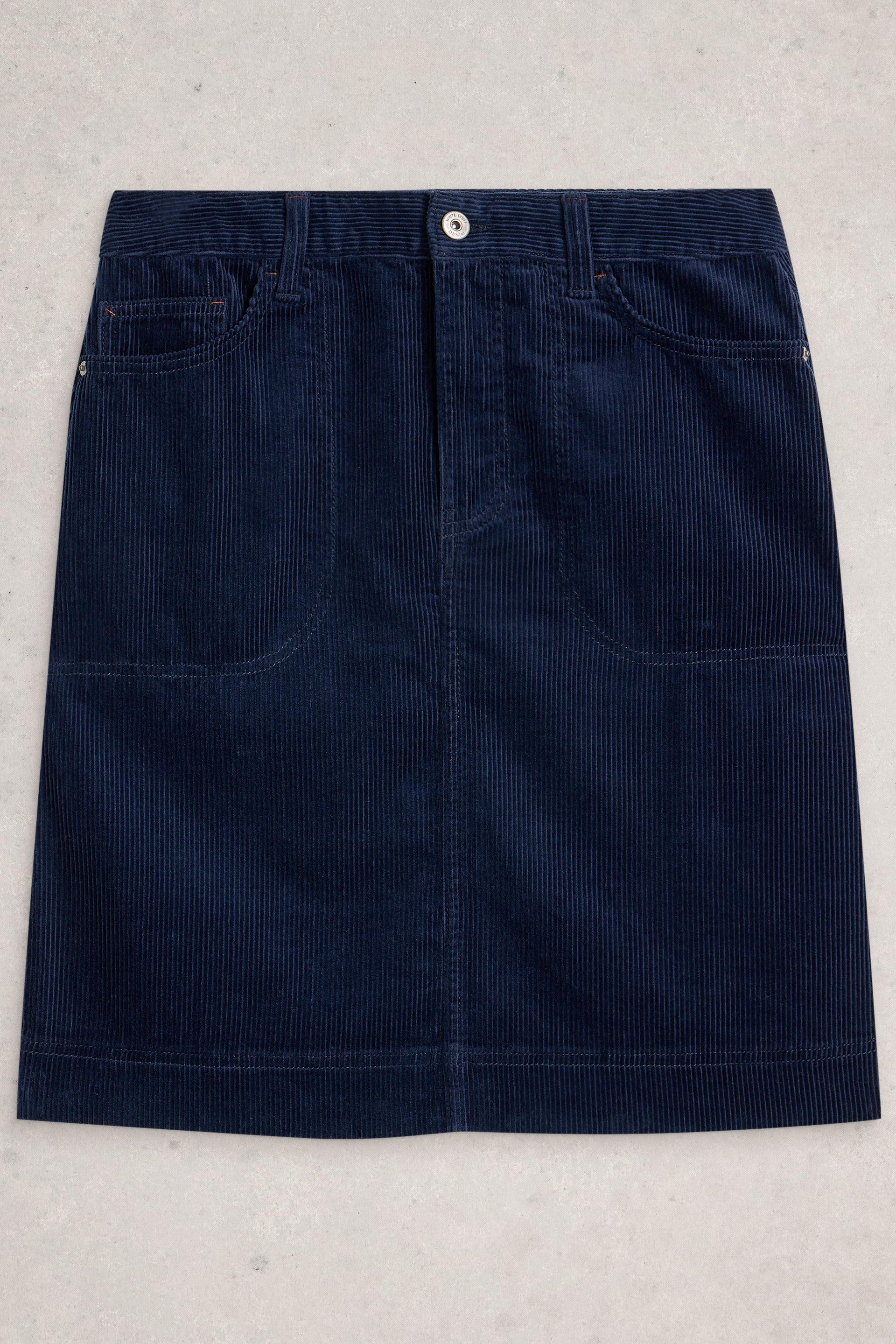 A dark navy blue corduroy skirt with a button closure at the waistband and two large front patch pockets, laid flat on a light gray textured background.