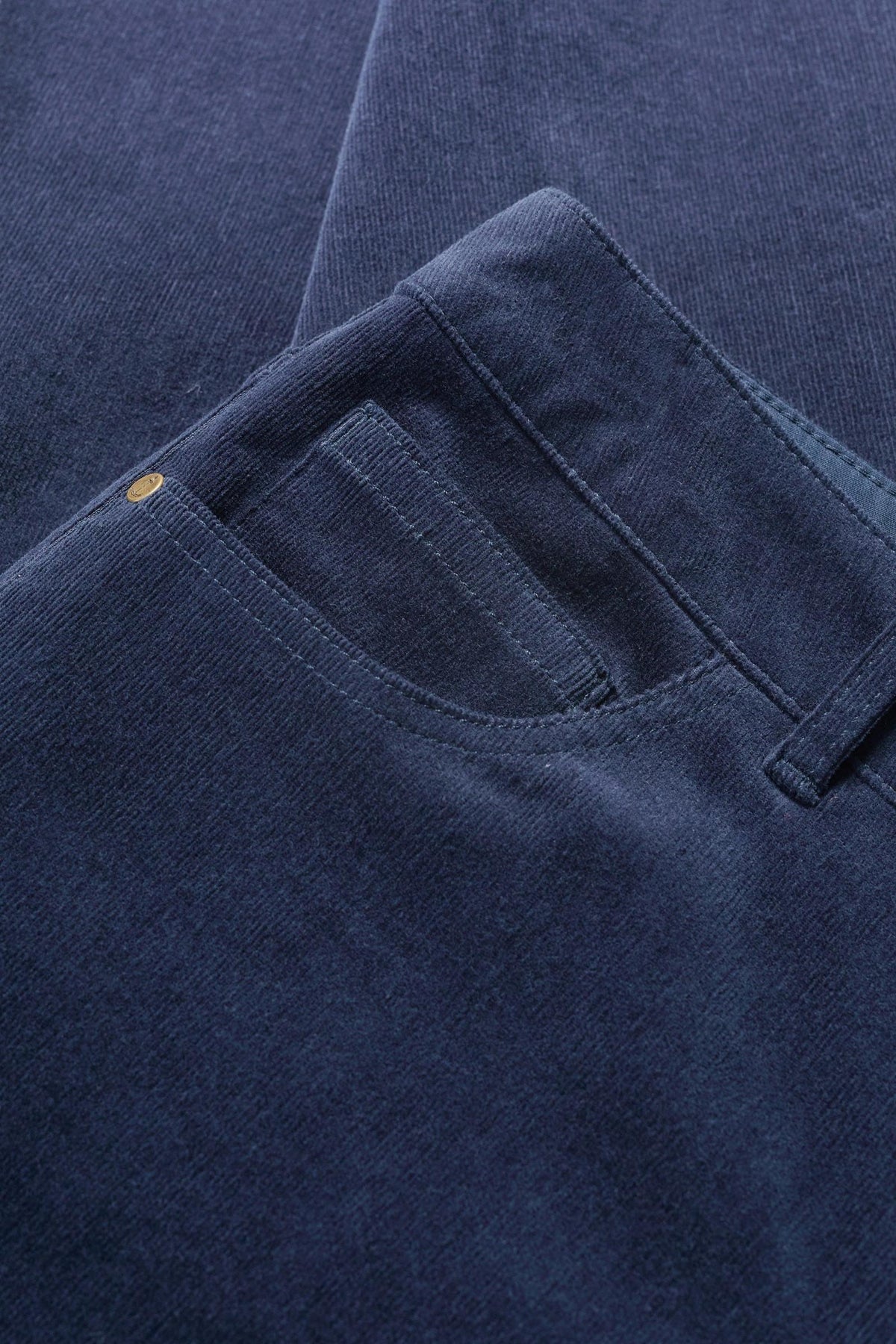 Close-up of navy blue organic cotton corduroy trousers showing pocket and texture.