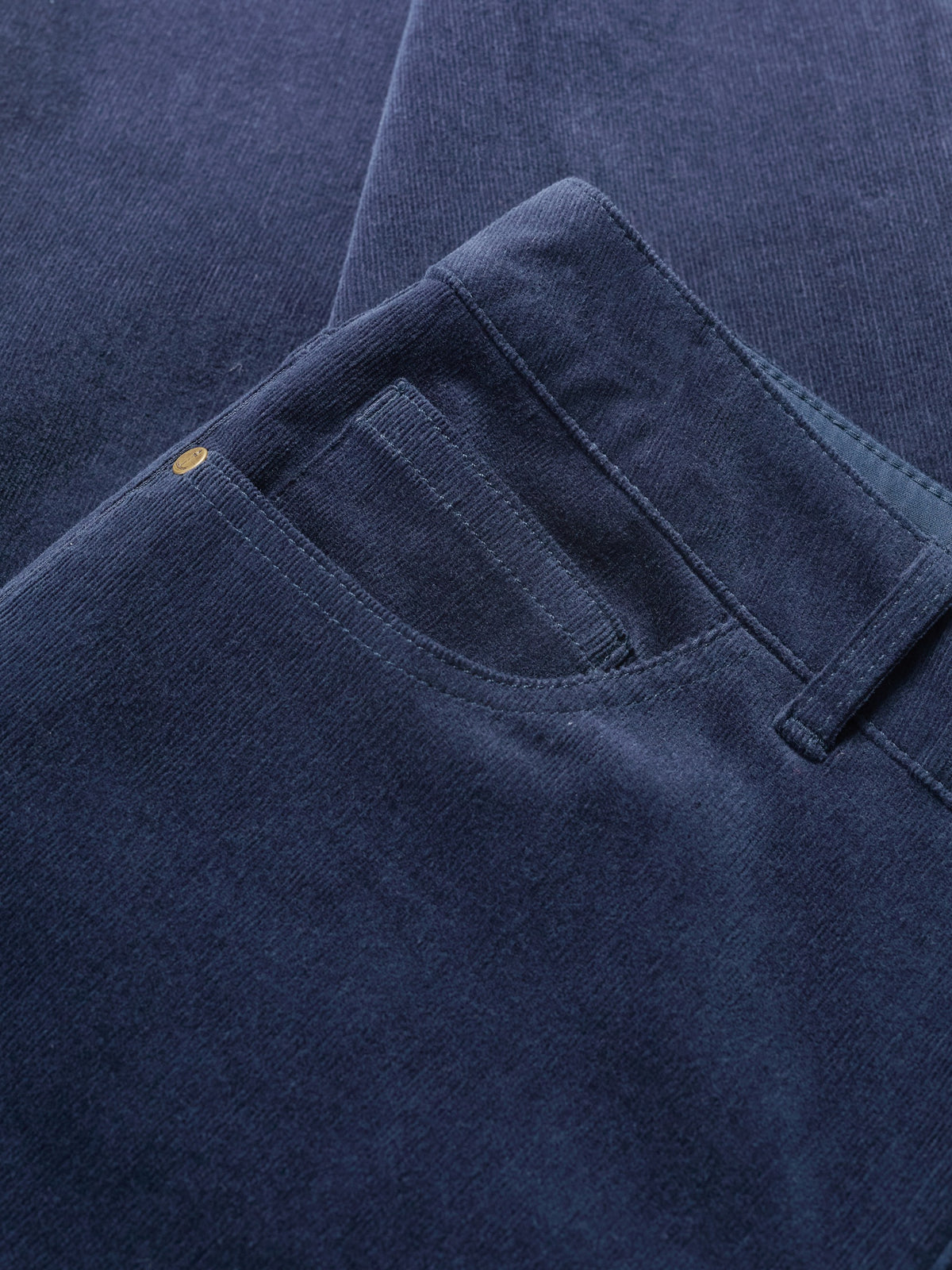 Close-up of navy blue organic cotton corduroy trousers showing pocket and texture.