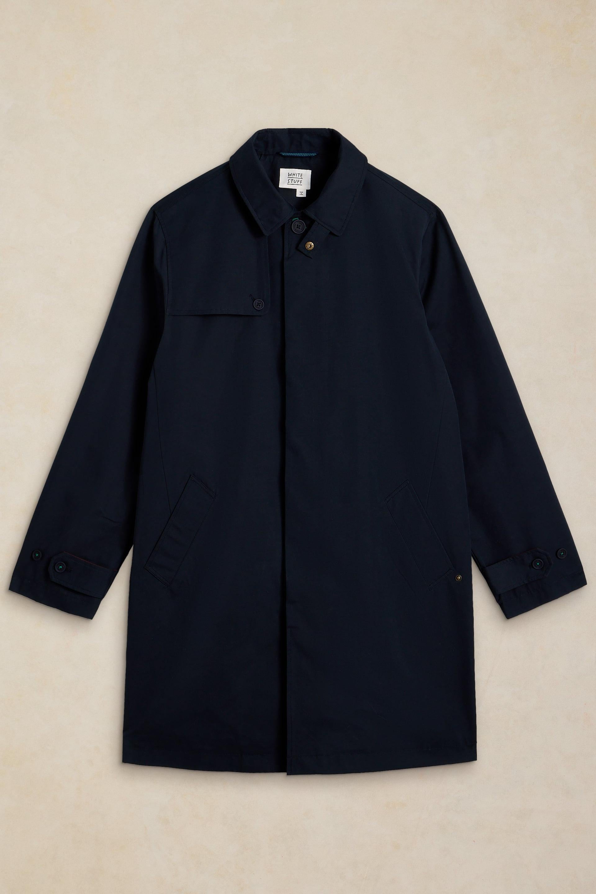 A dark navy blue utility jacket with a collar, button front, and flap chest pocket, laid flat against a textured beige background.