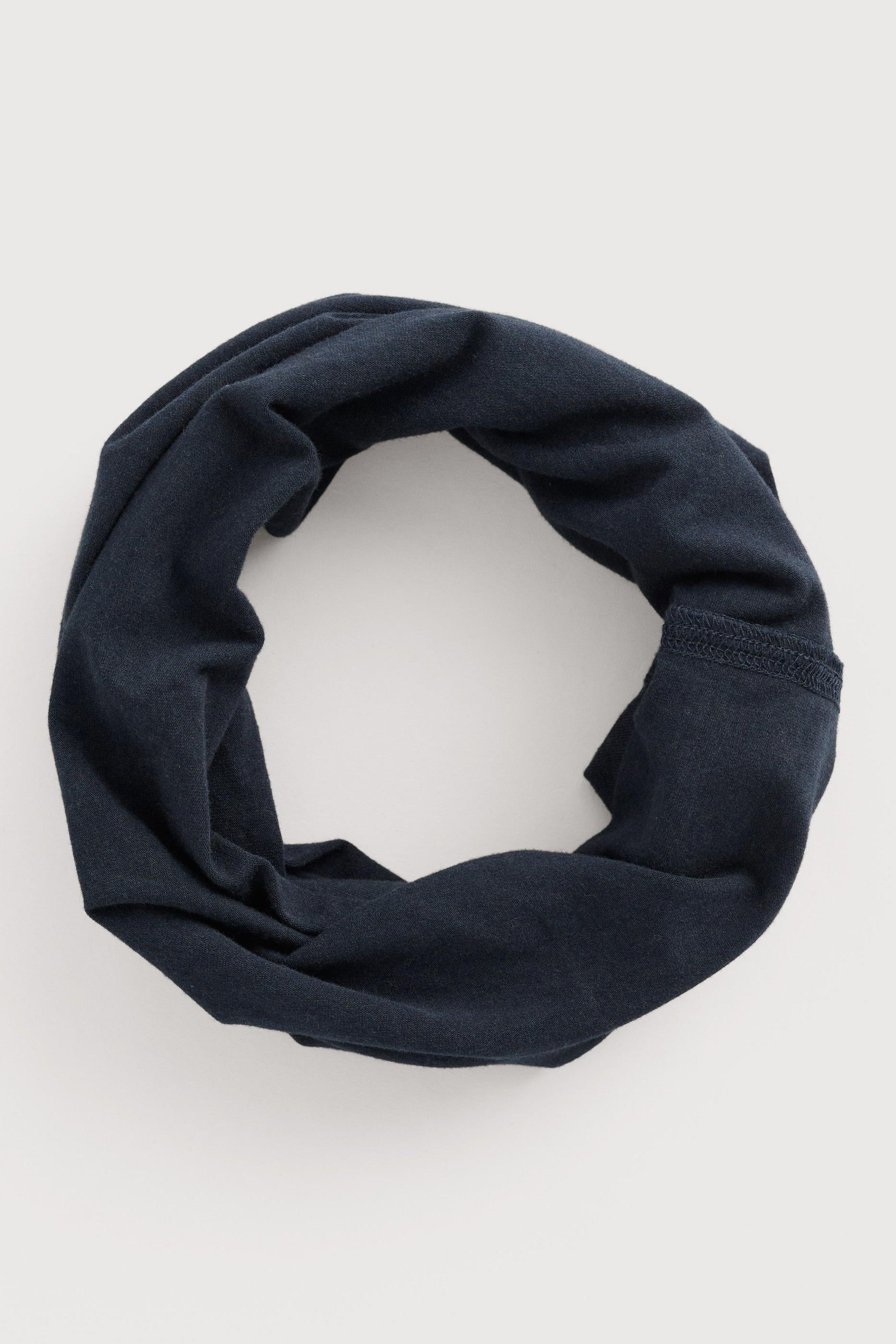 A dark navy blue knit infinity scarf, styled in a loose loop, photographed flat on a light gray background.