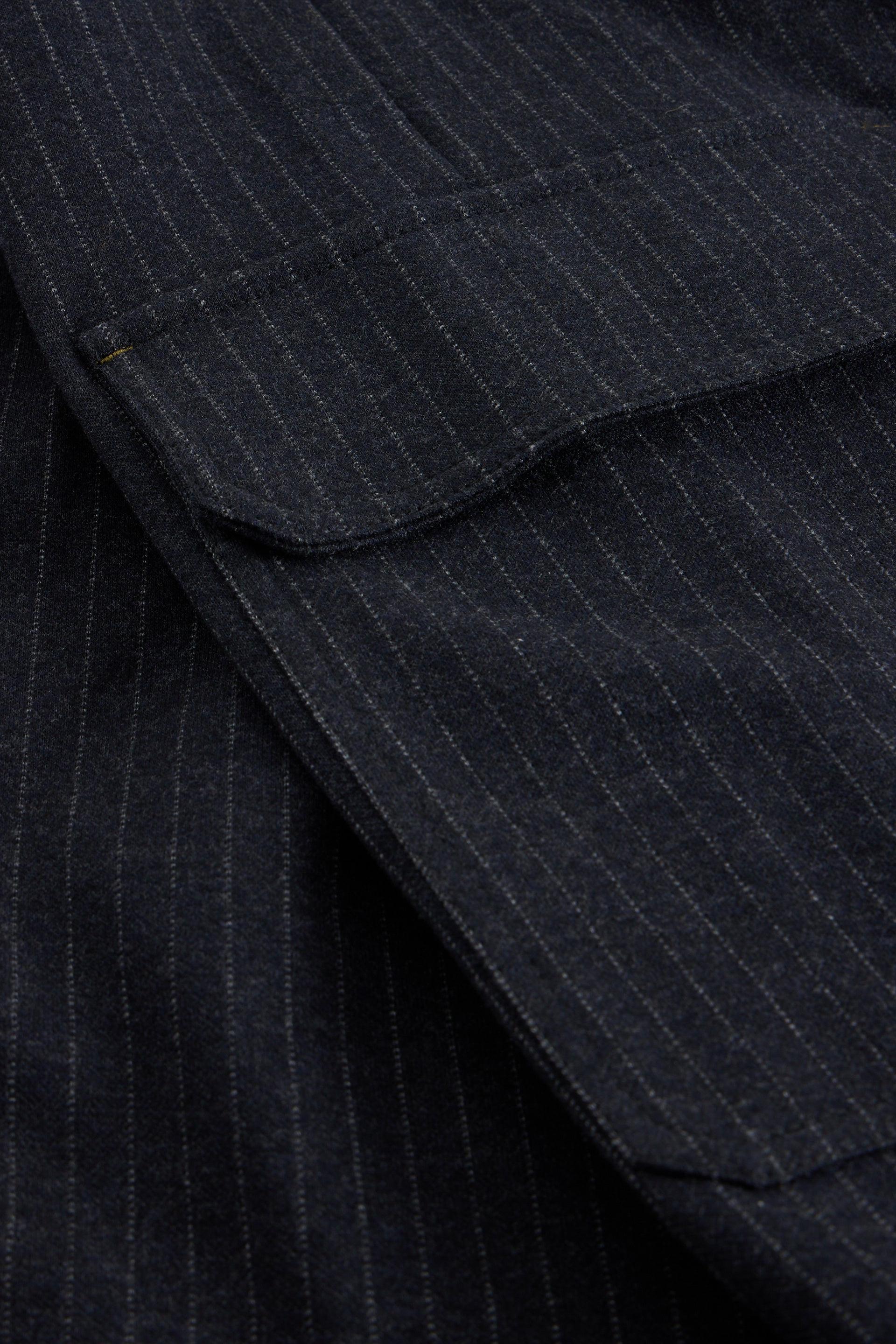 Close-up of dark navy blue pinstriped fabric with a pocket detail.