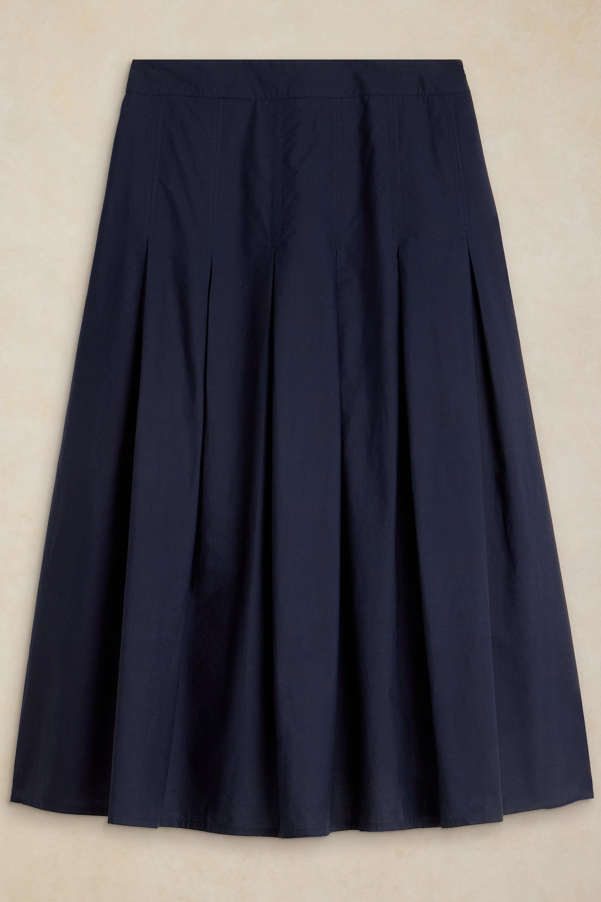A navy blue pleated midi skirt made from organic cotton displayed against a neutral background