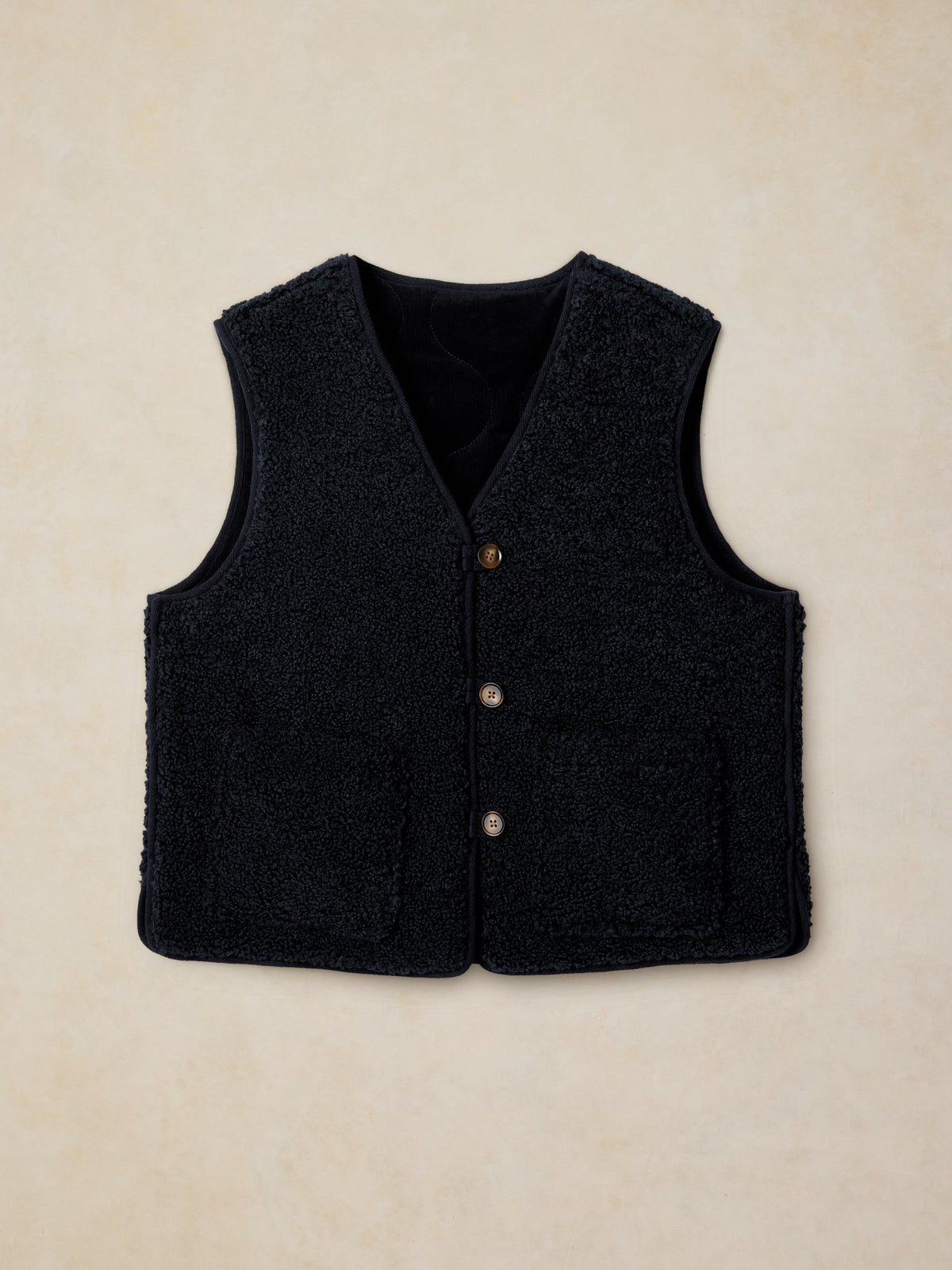 Navy women's reversible gilet made from recycled polyester, featuring a textured fleece finish and button-up front.