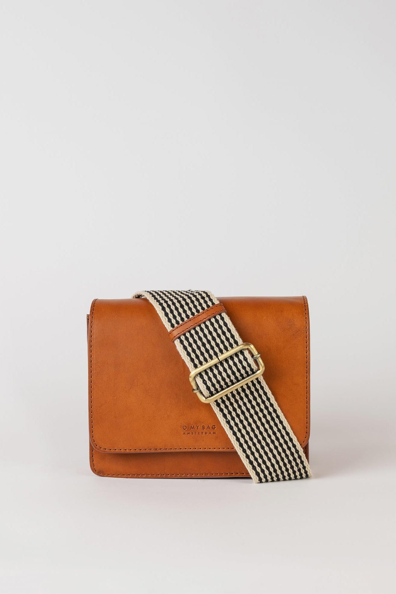 Brown leather handbag with a striped strap on a light gray background