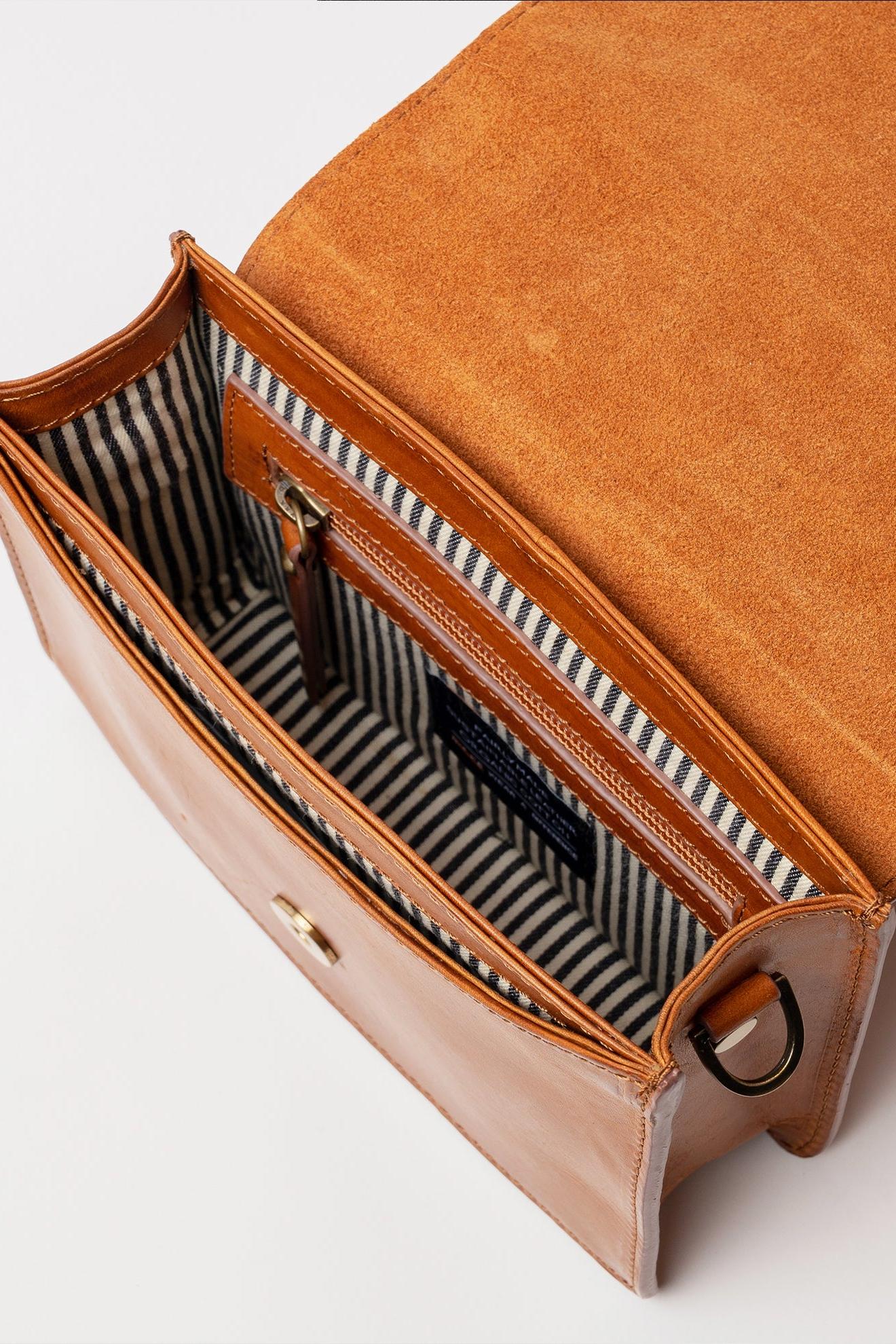 Brown leather handbag with striped lining on a white background