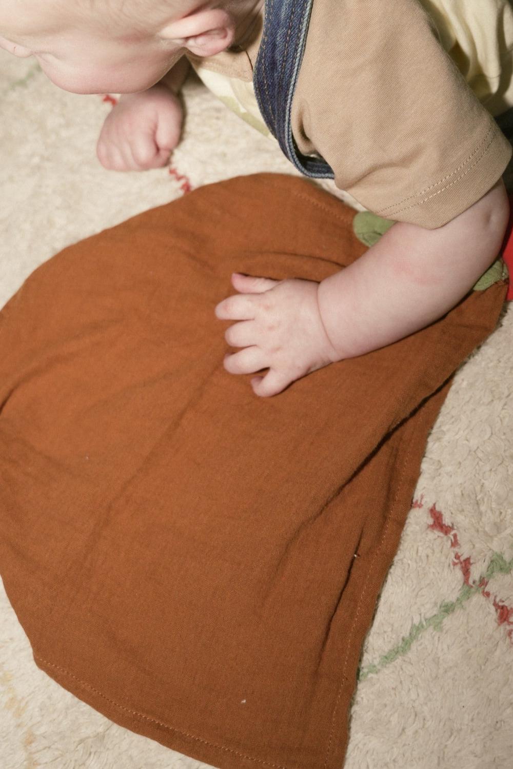 Baby interacting with an organic cotton comforter on a carpeted floor