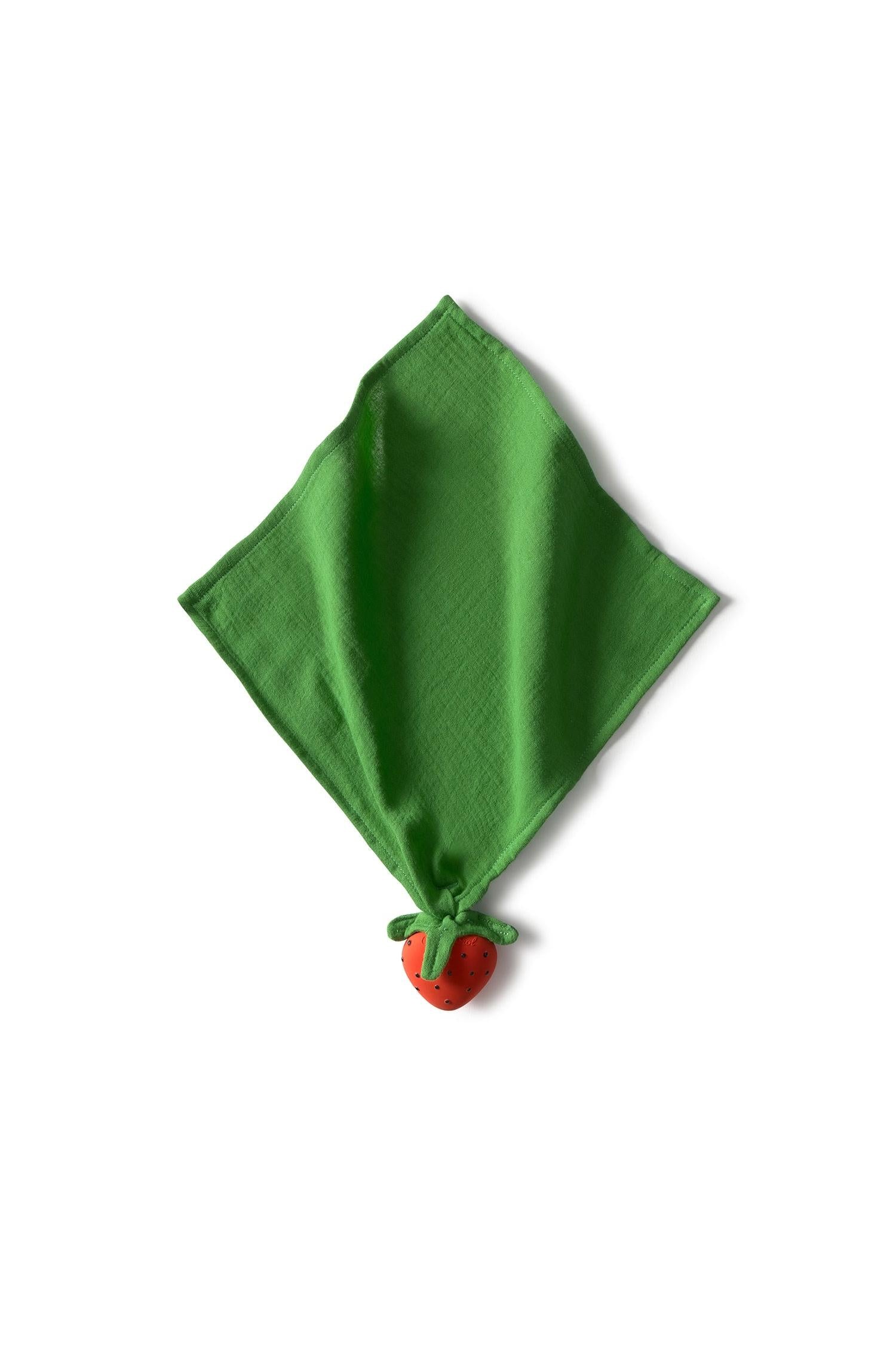 Green organic cotton fabric square with a small red and green strawberry doudou on a white background