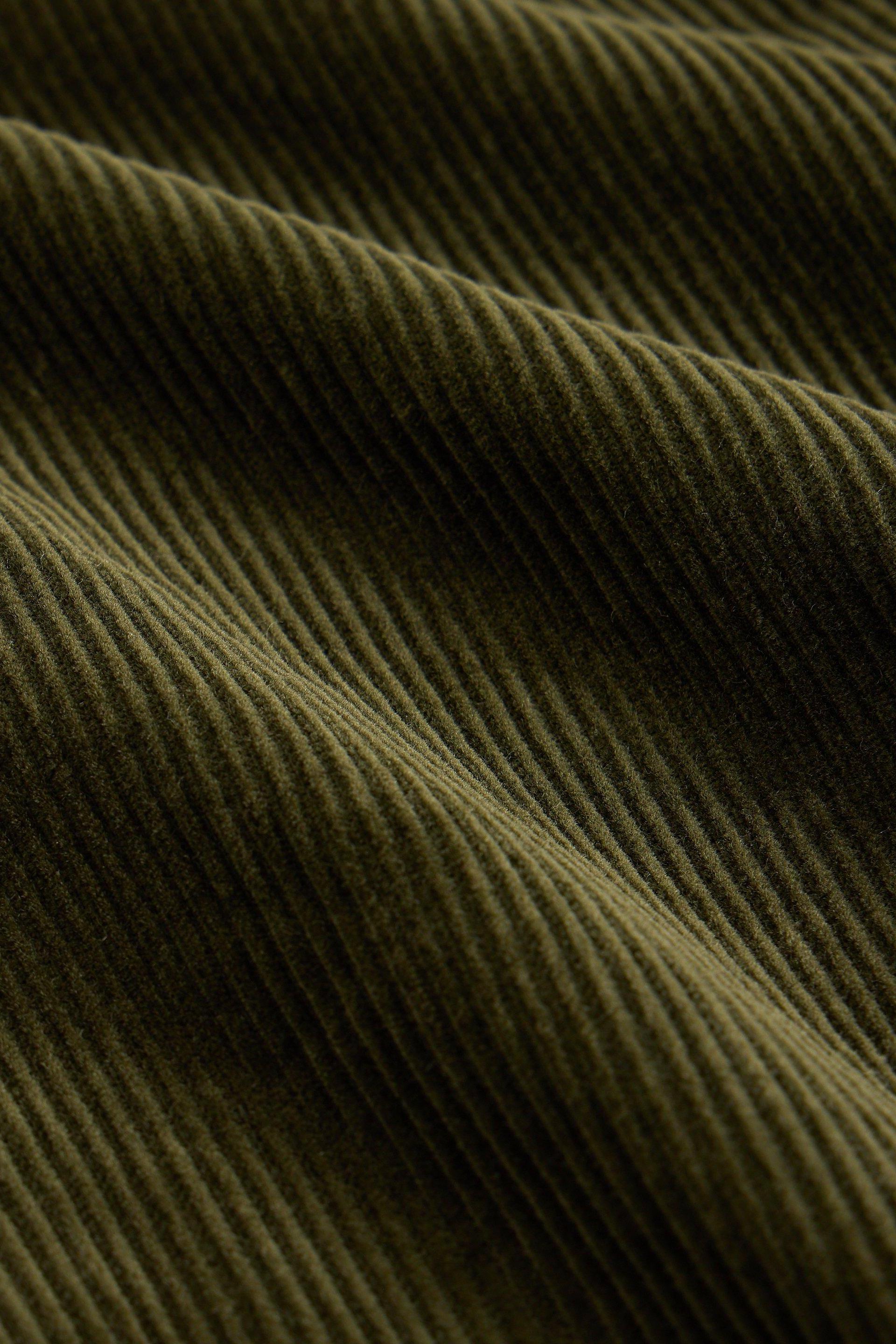 Close-up of olive green corduroy fabric showing the texture and ridges of an organic cotton skirt.