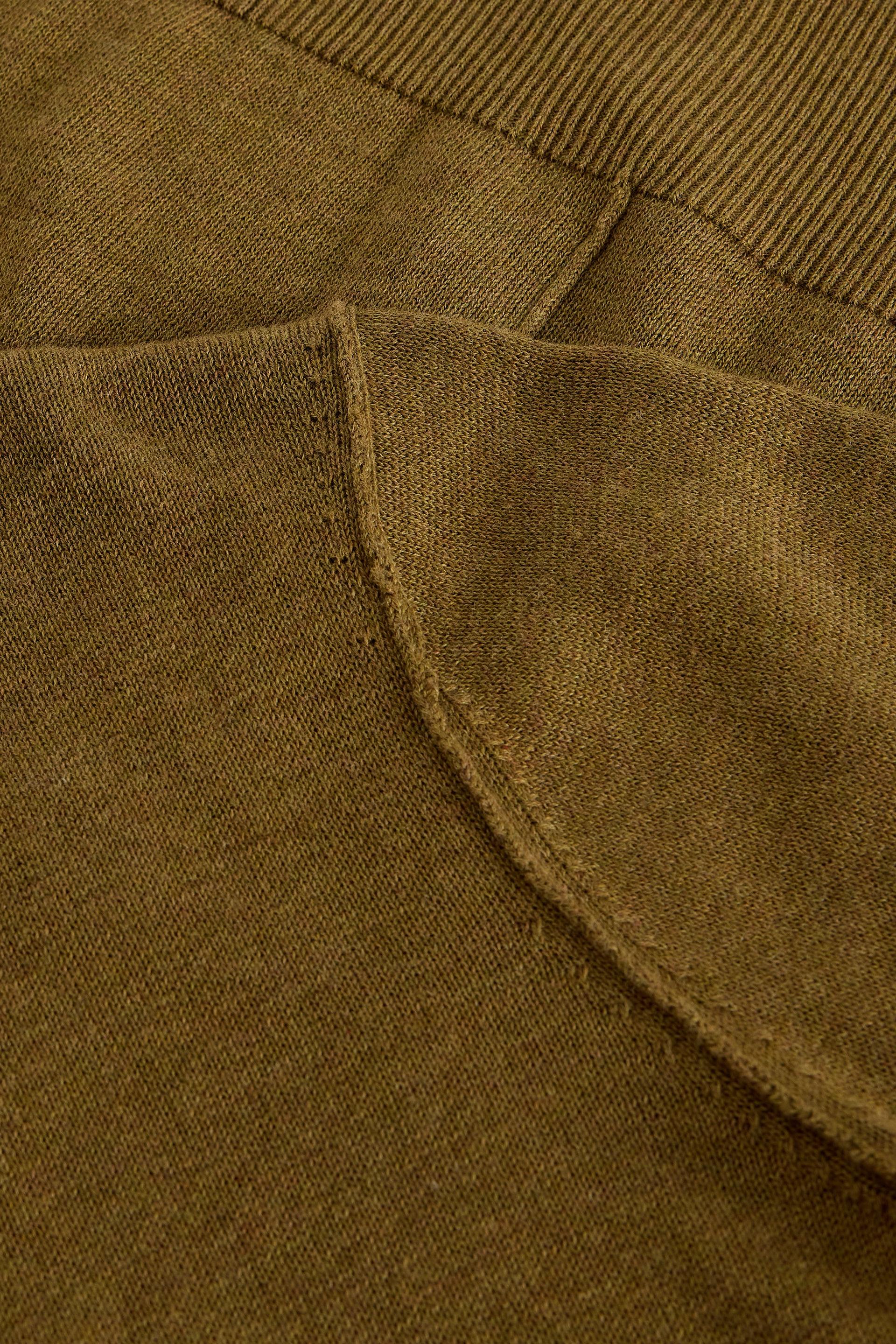 Close-up of olive green organic cotton knit fabric showing the seam and ribbed texture detail