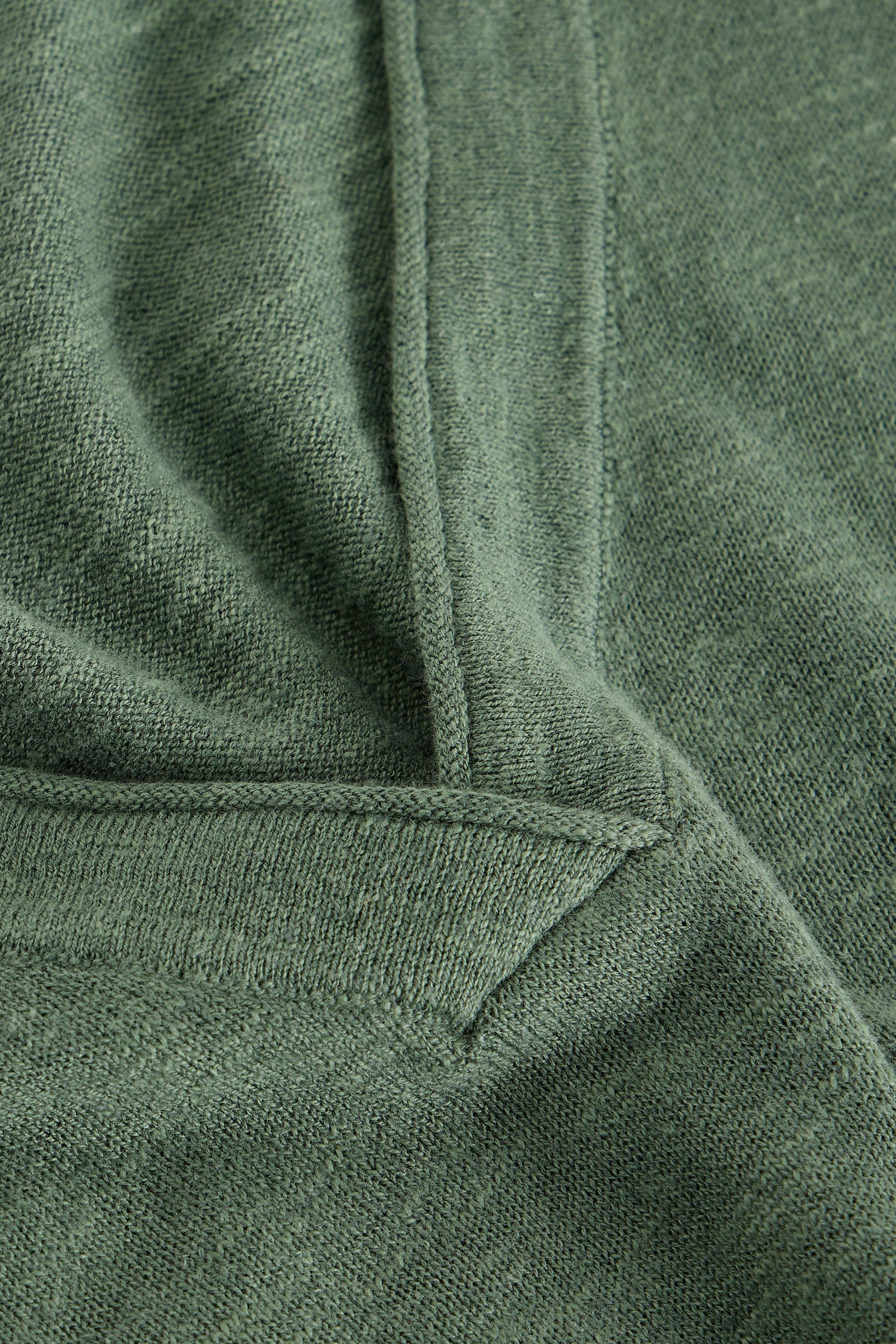 Close-up of the neckline and texture of an olive green organic cotton v-neck sweater.