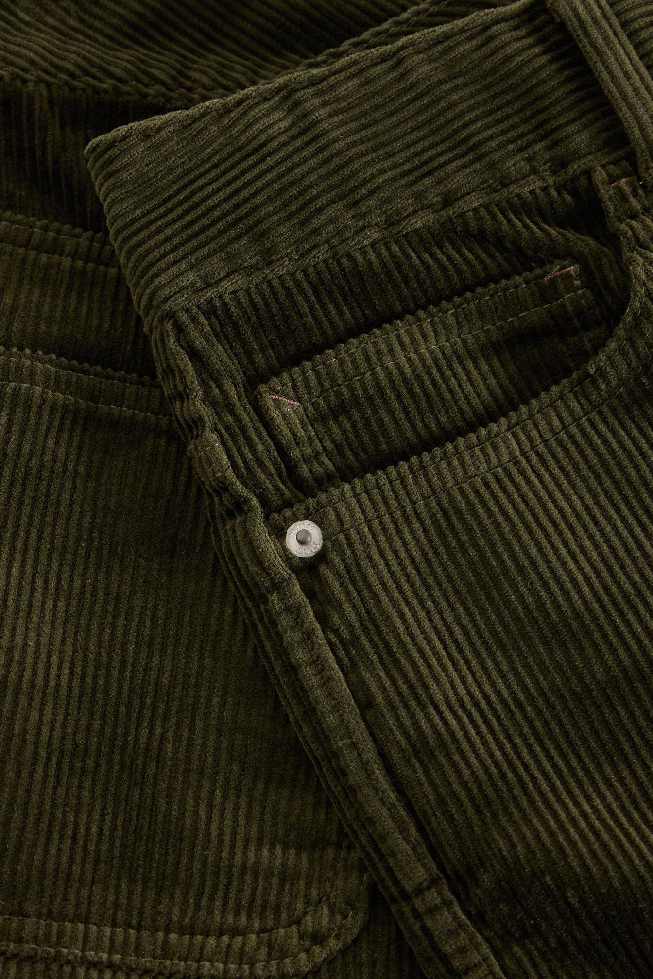 Close up of olive green corduroy fabric on White Stuff women's trousers with a metallic rivet detail.