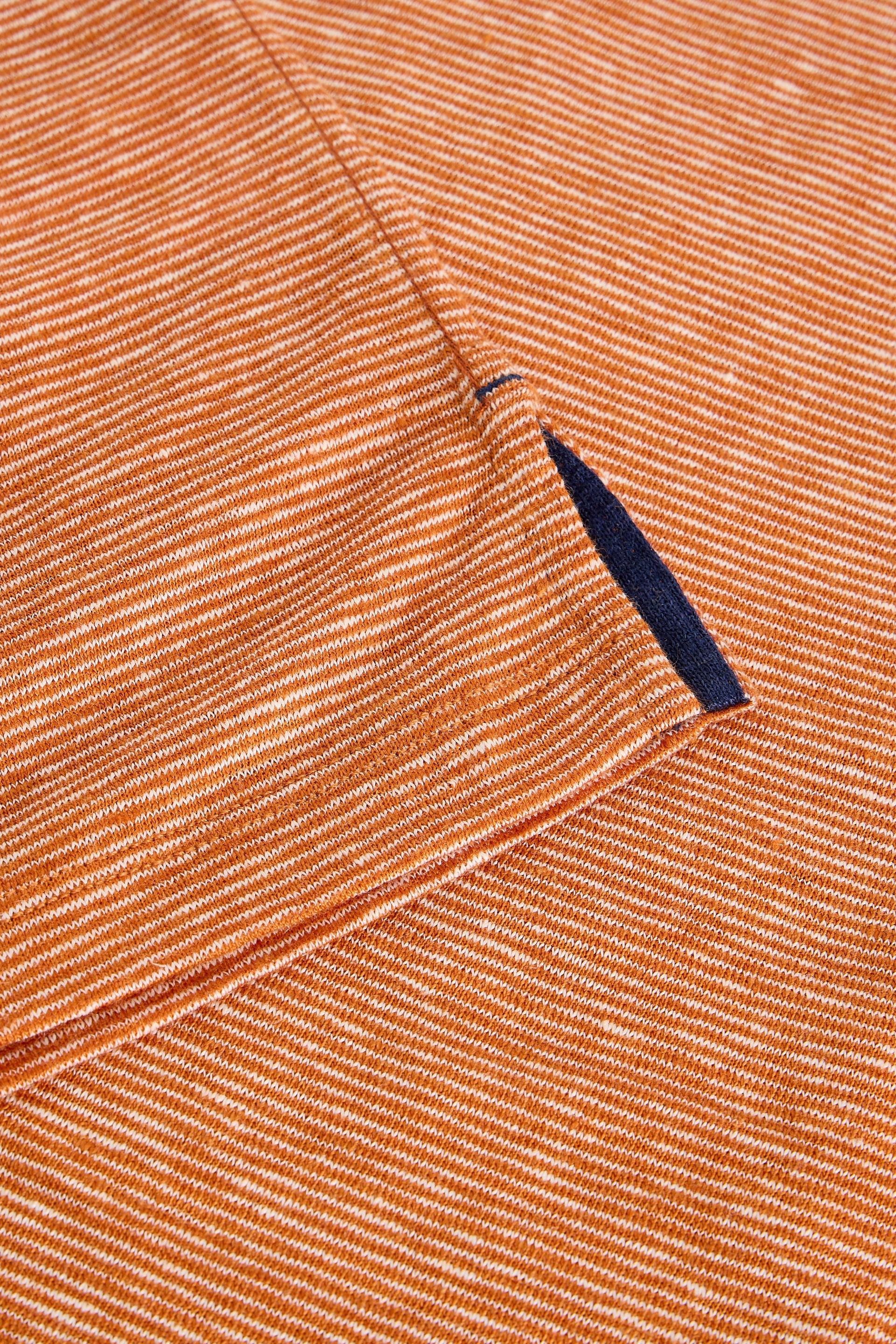 Close up of orange and white striped sustainable 100% linen t-shirt fabric with navy trim.